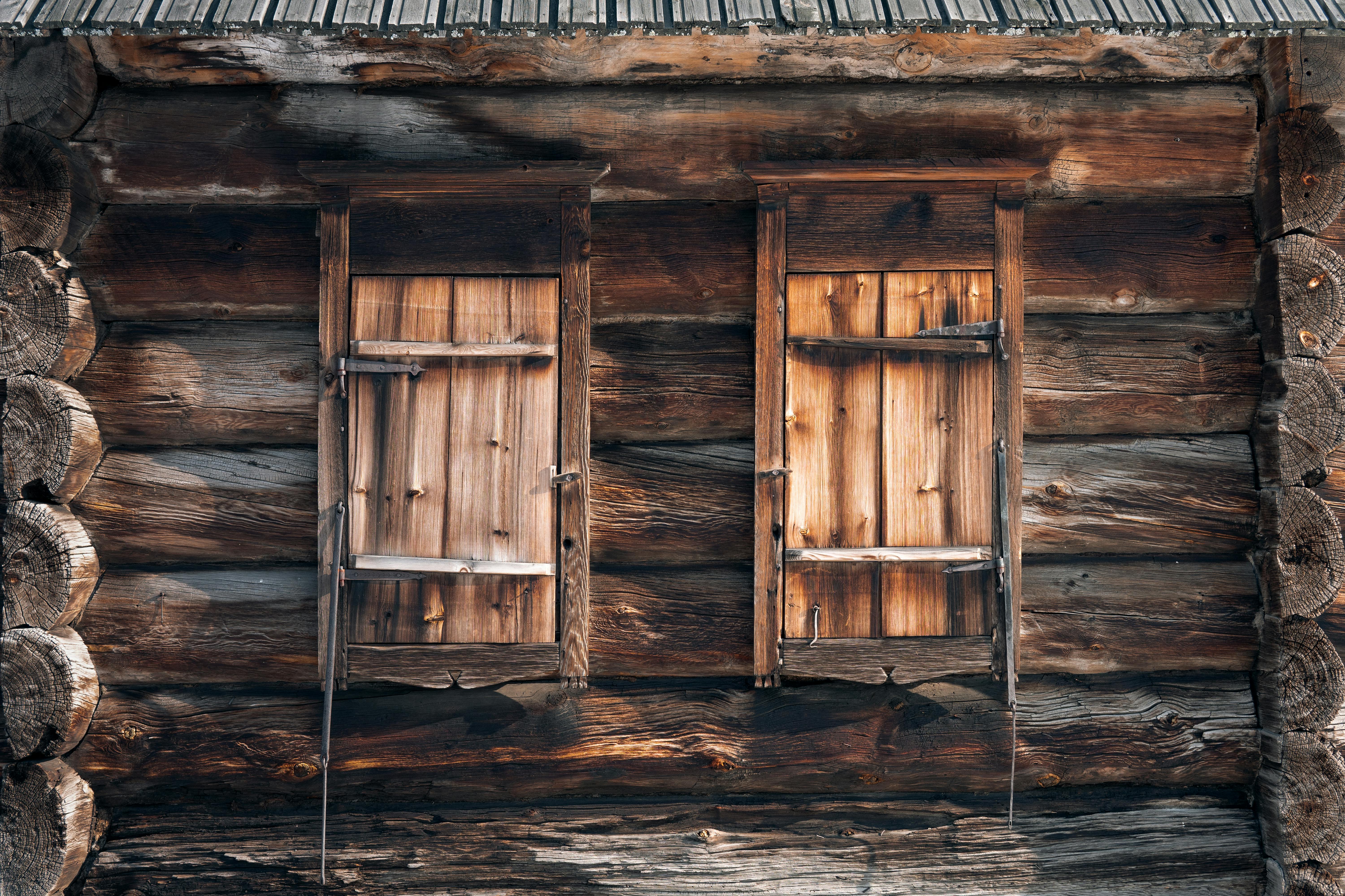 Detail of exterior of shabby rustic house made of wooden logs with closed windows on sunny day