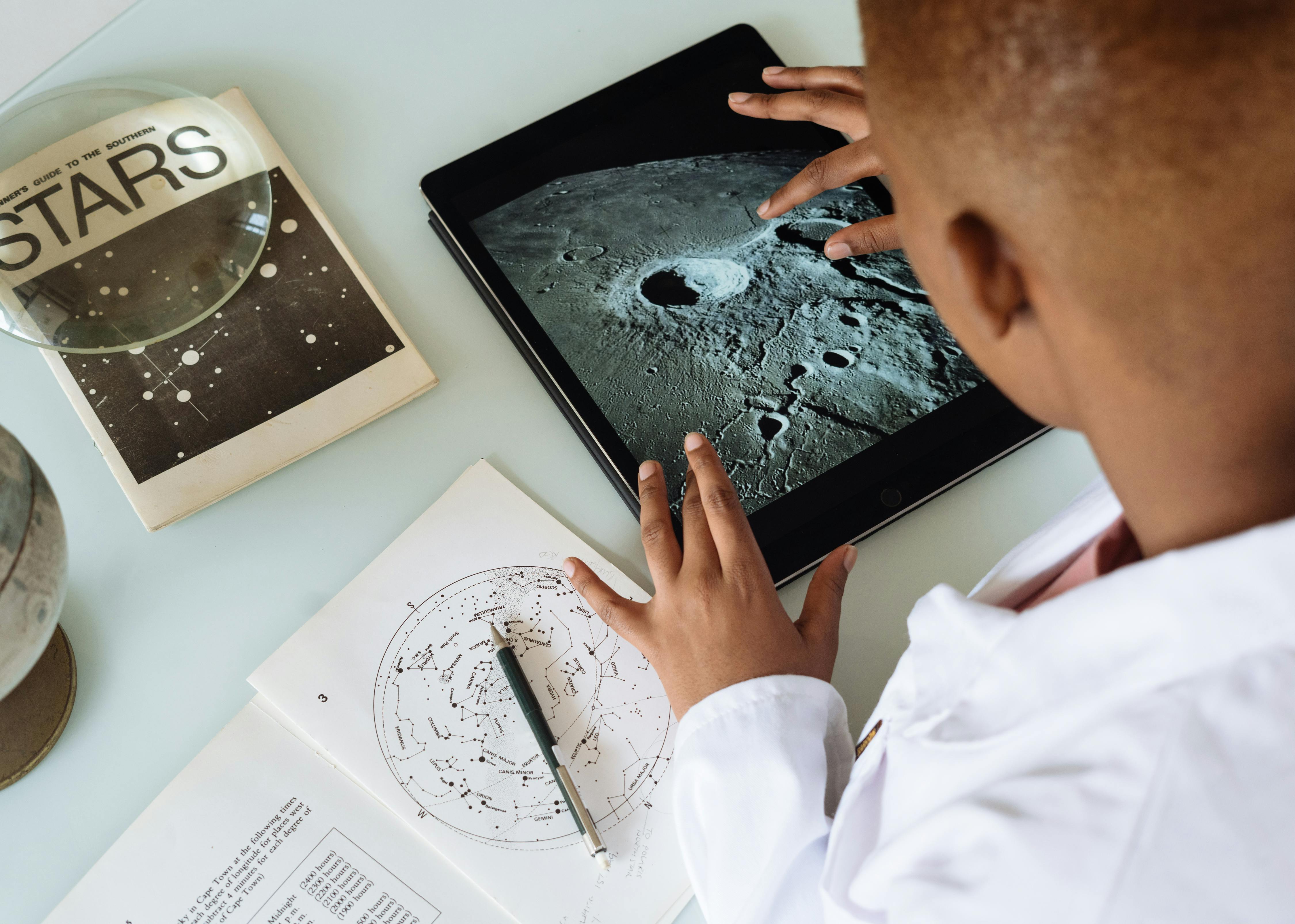 Crop African American student studying craters of moon on tablet at observatory