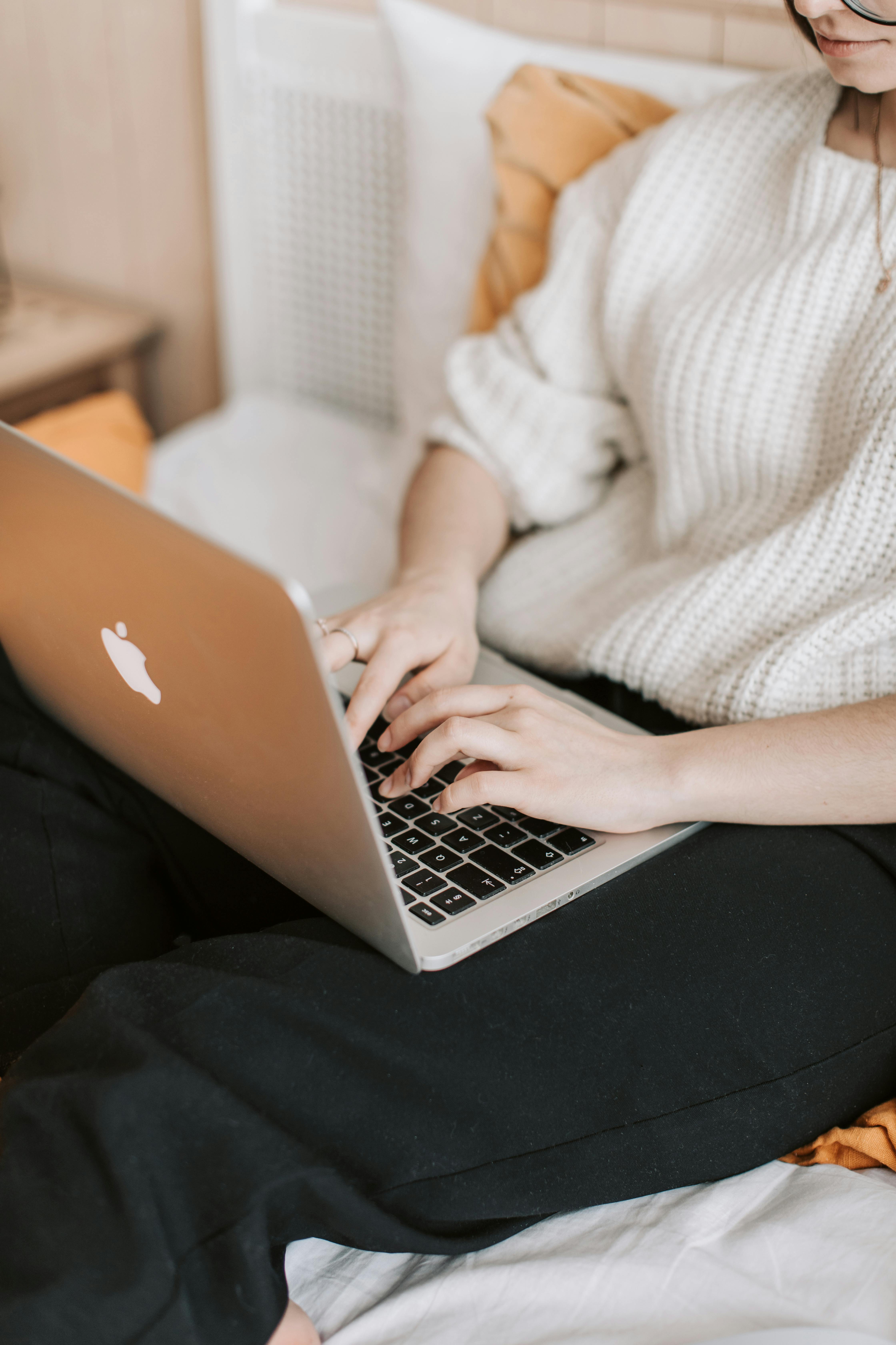 Crop woman typing on laptop on bed