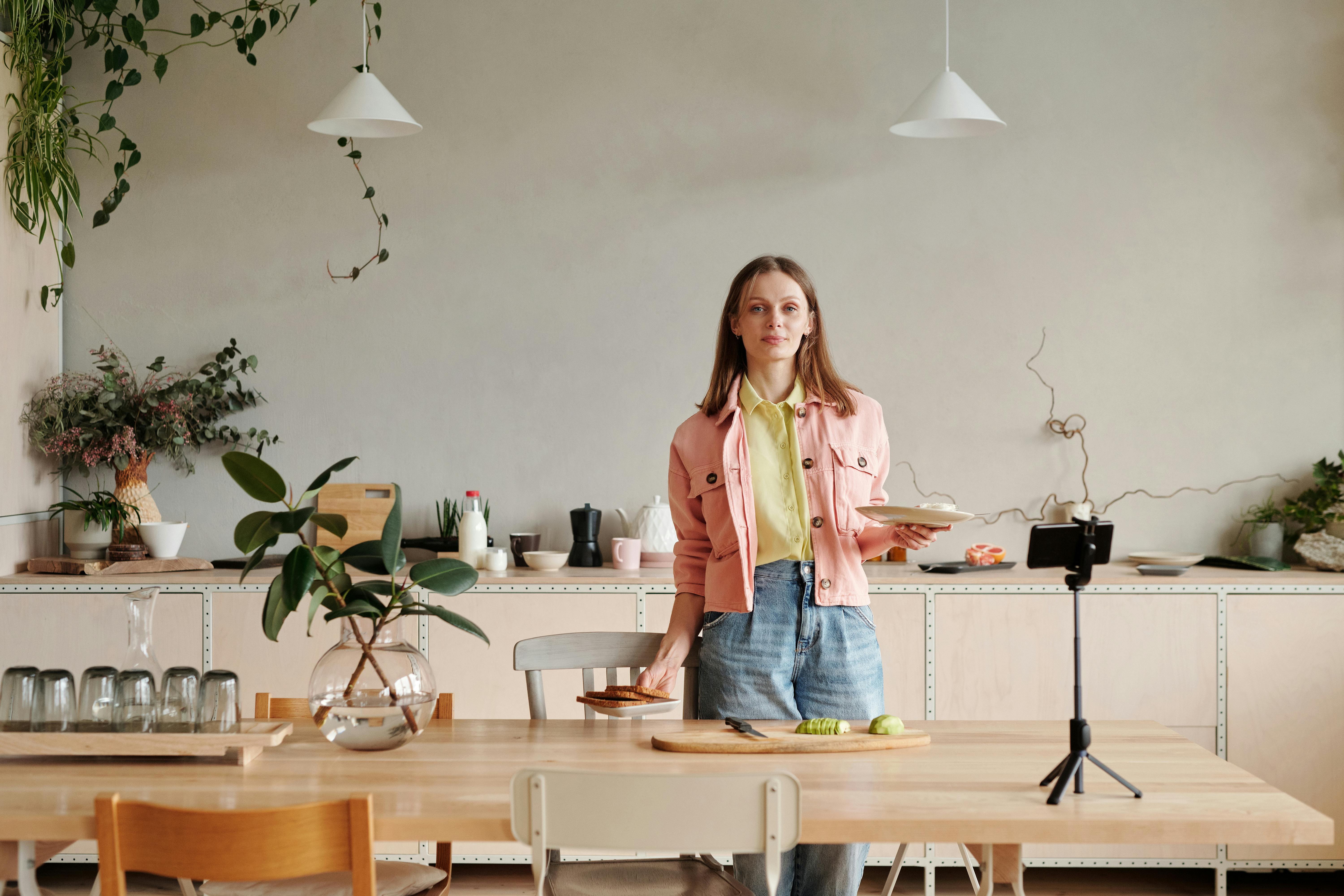 Woman in Pink Jacket Standing Beside Brown Wooden Table