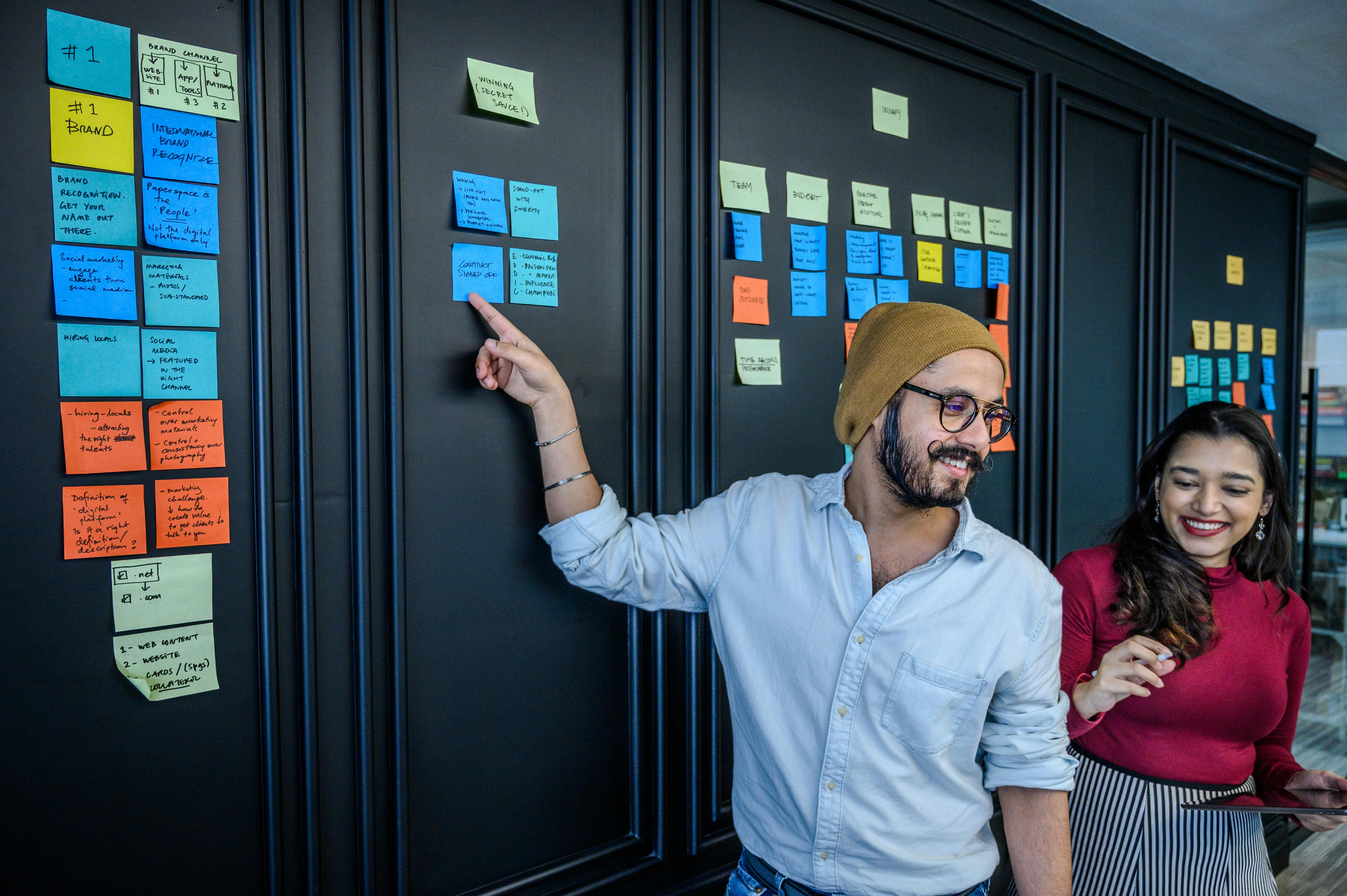 A Man in Brown Beanie Pointing at Sticky Notes