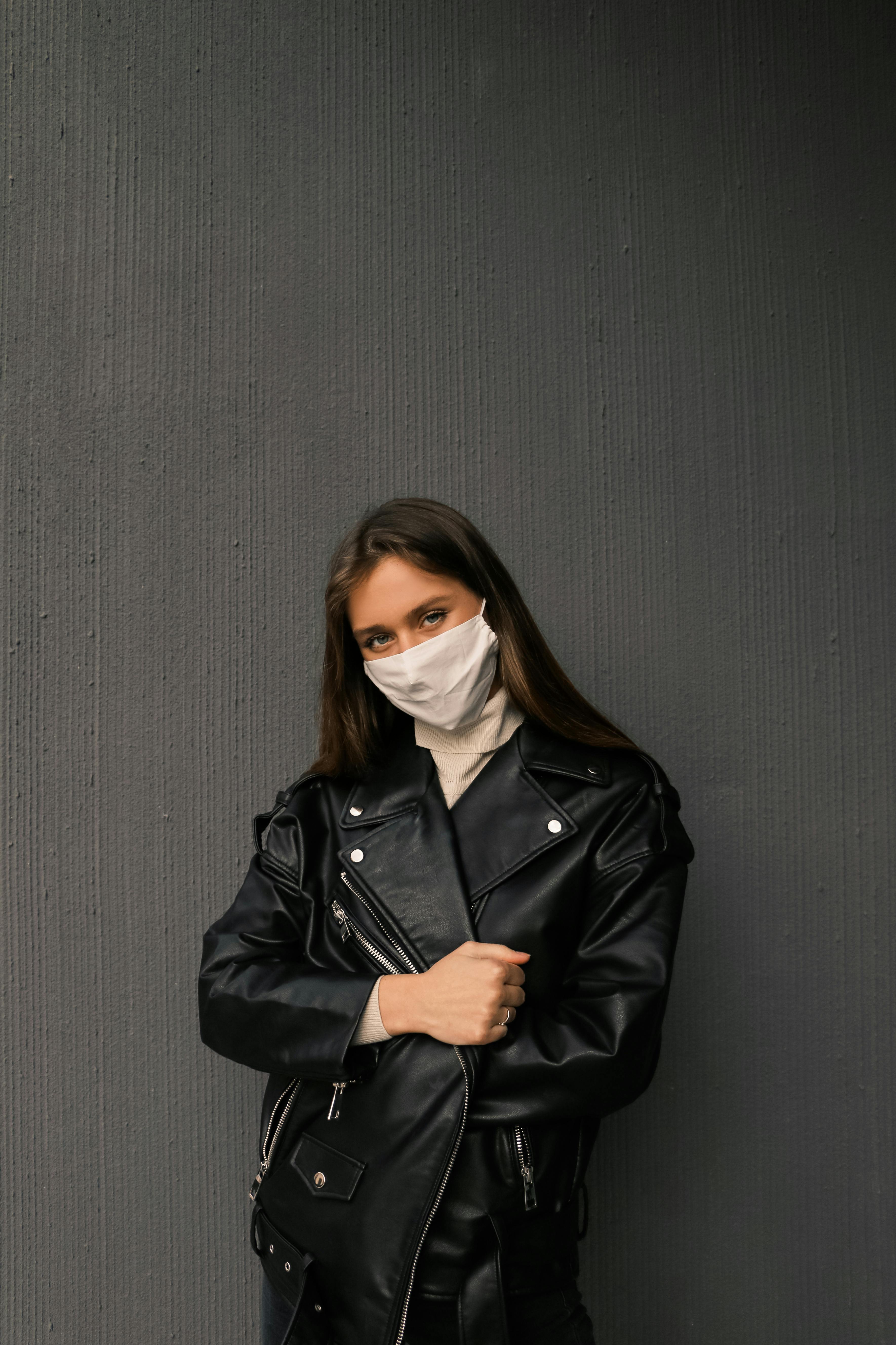 
A Woman Wearing a Black Leather Jacket and a Face Mask