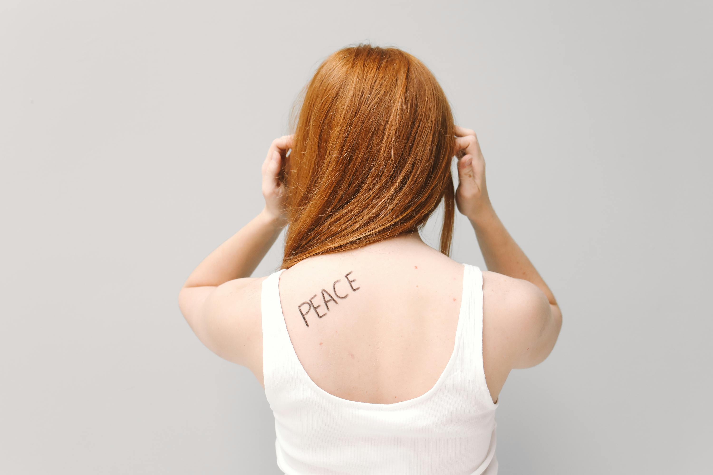 Woman in White Tank Top with Word "Peace" Written on Her Back