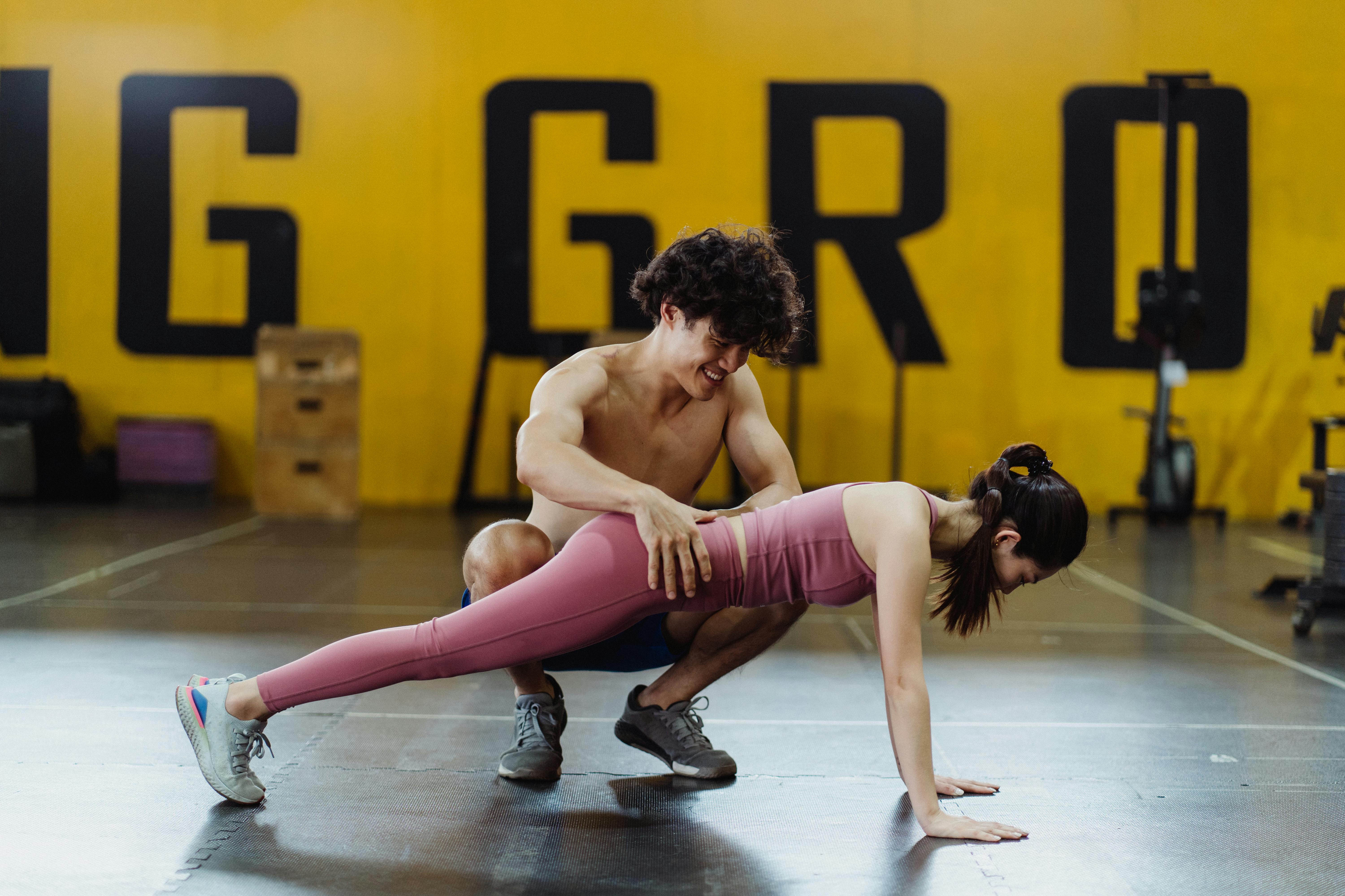 A Man Assisting a Woman in Doing Push Ups