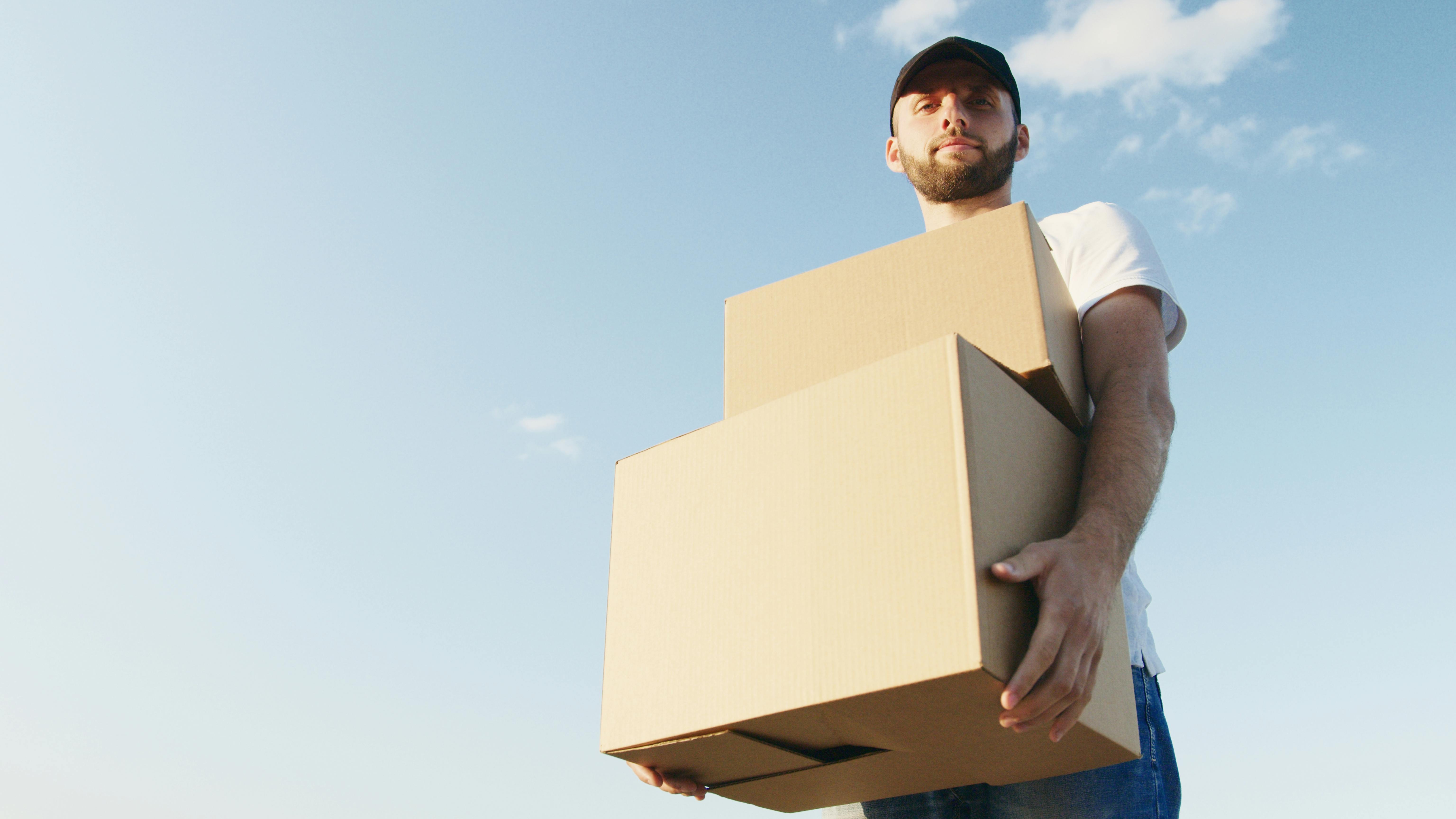 Man in White T-shirt Holding Brown Box