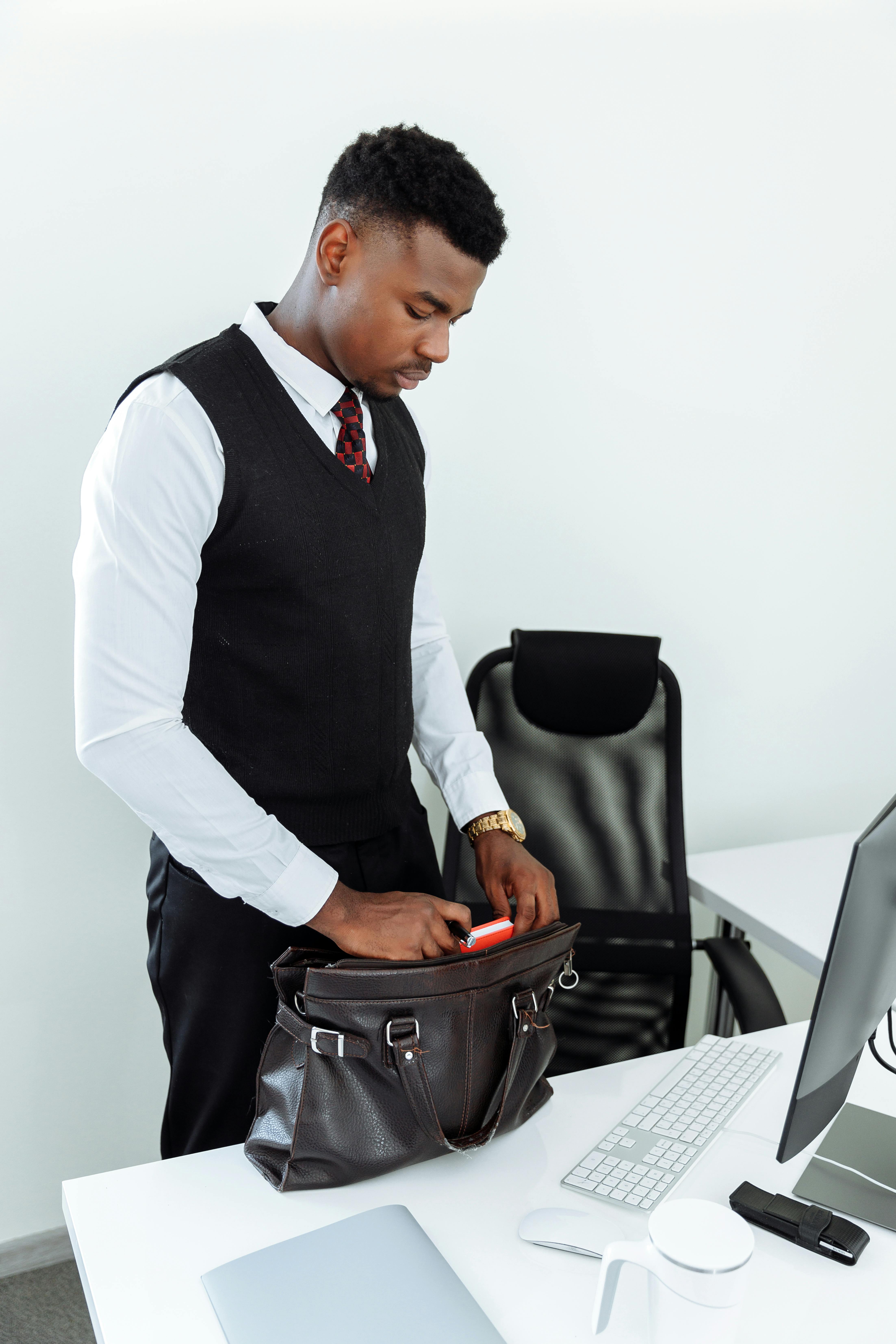 Man in White Dress Shirt and Black Vest Sitting on Black Office Rolling Chair