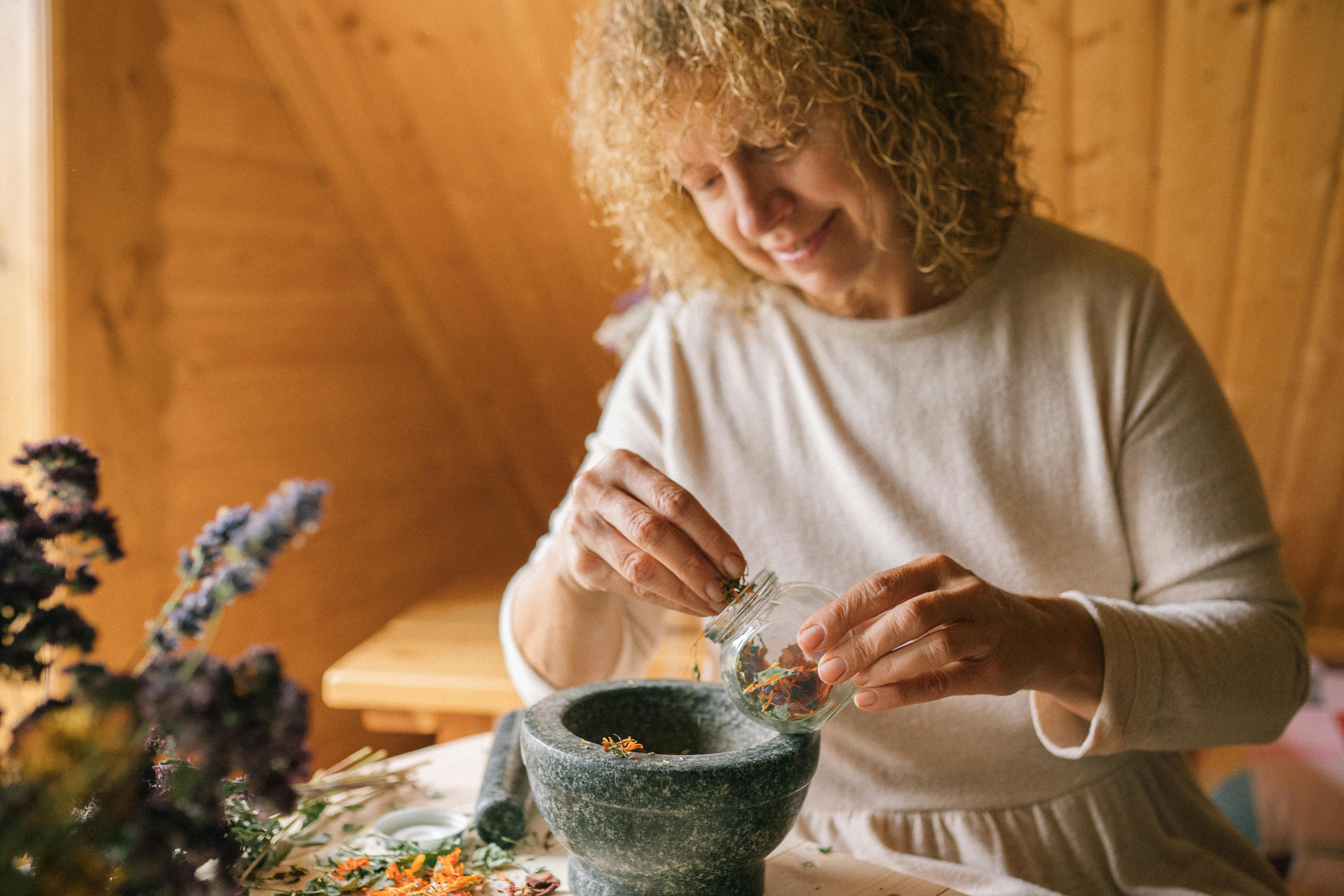 A Woman Placing Grinded Flowers in a Bottle