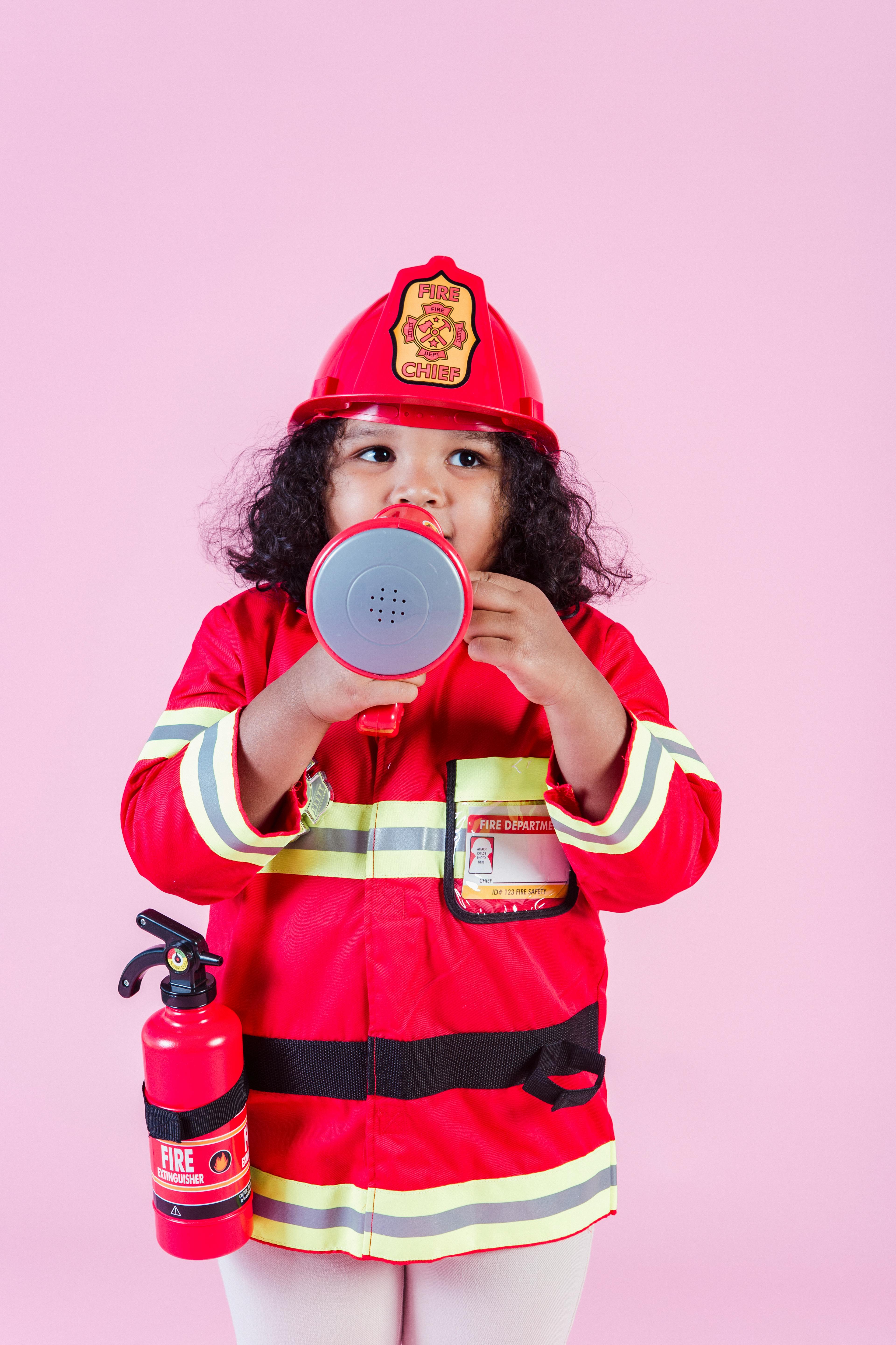 Ethnic girl wearing firefighter costume using megaphone