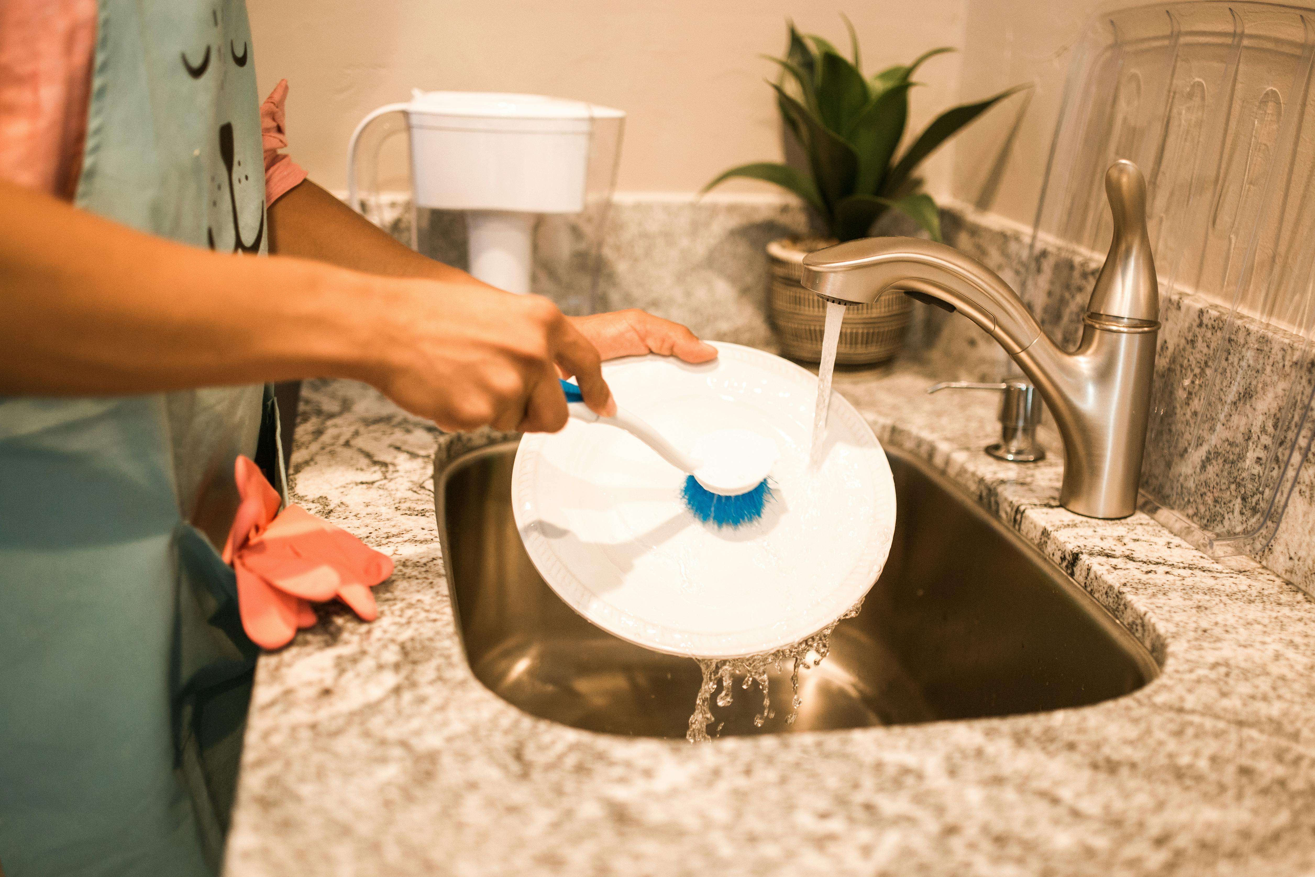 Photo of a Person's Hands Washing a White Plate