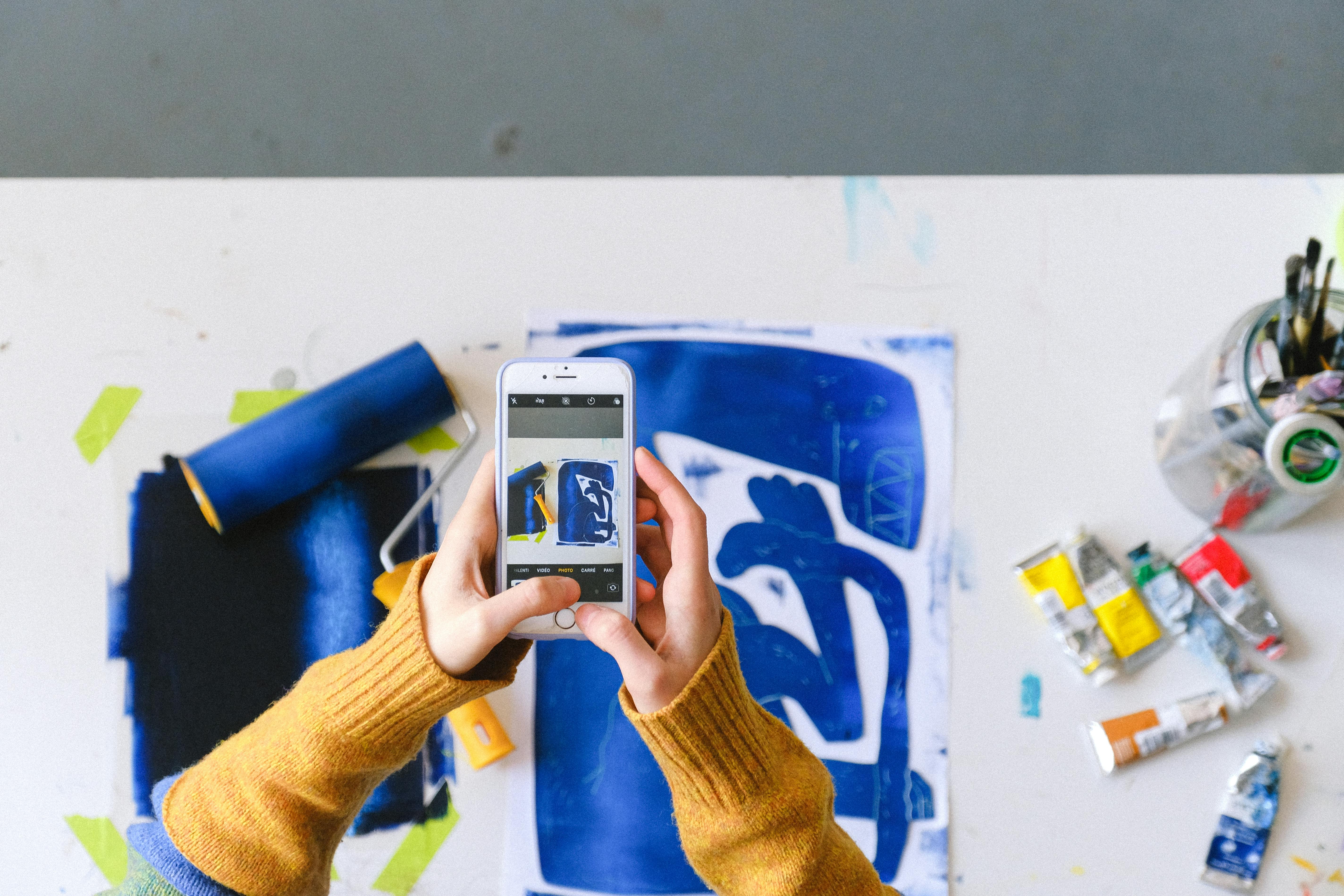 Woman taking photo of abstract picture on table