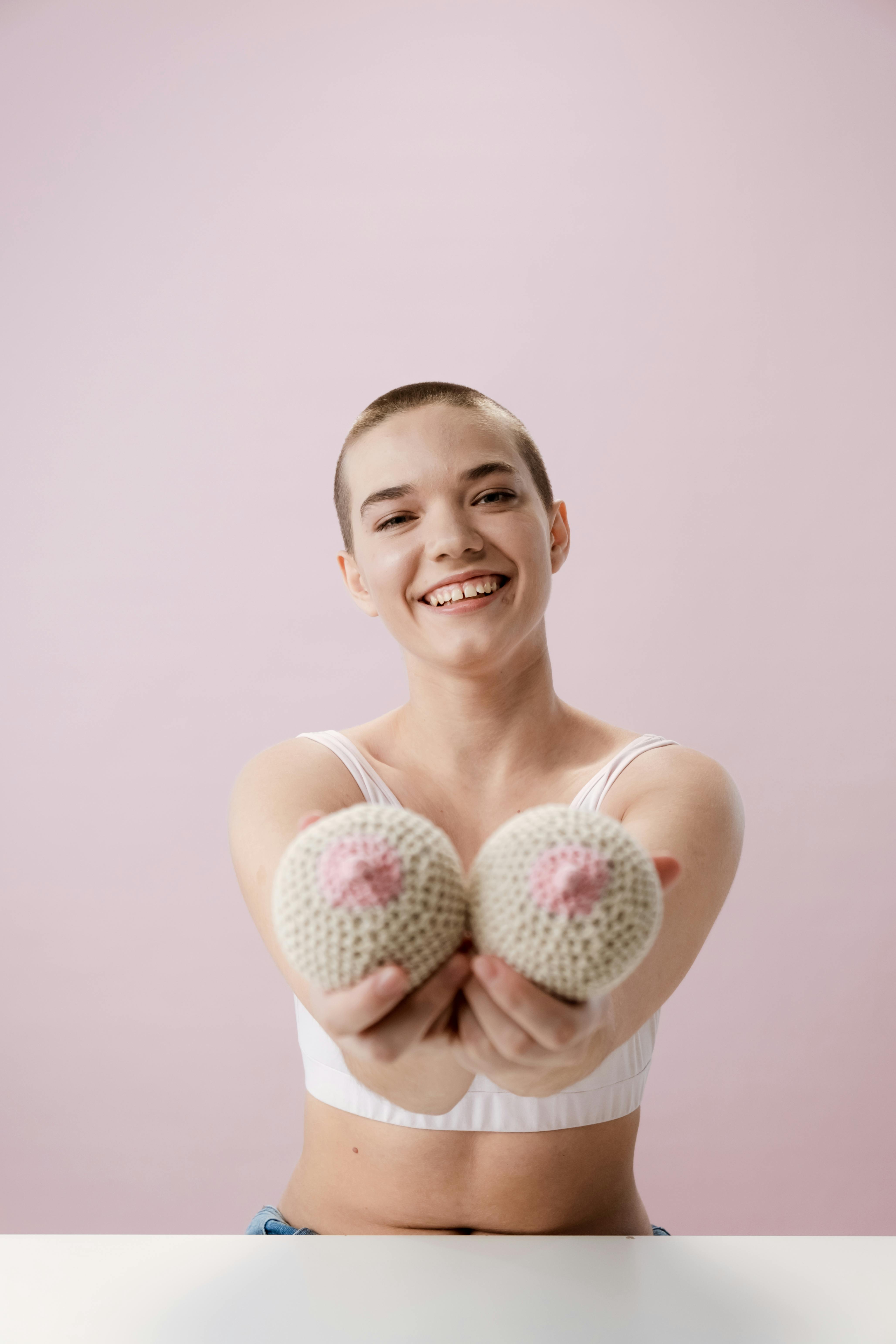 Smiling Woman in White Tank Top Holding Two Pink and White Round Fruits