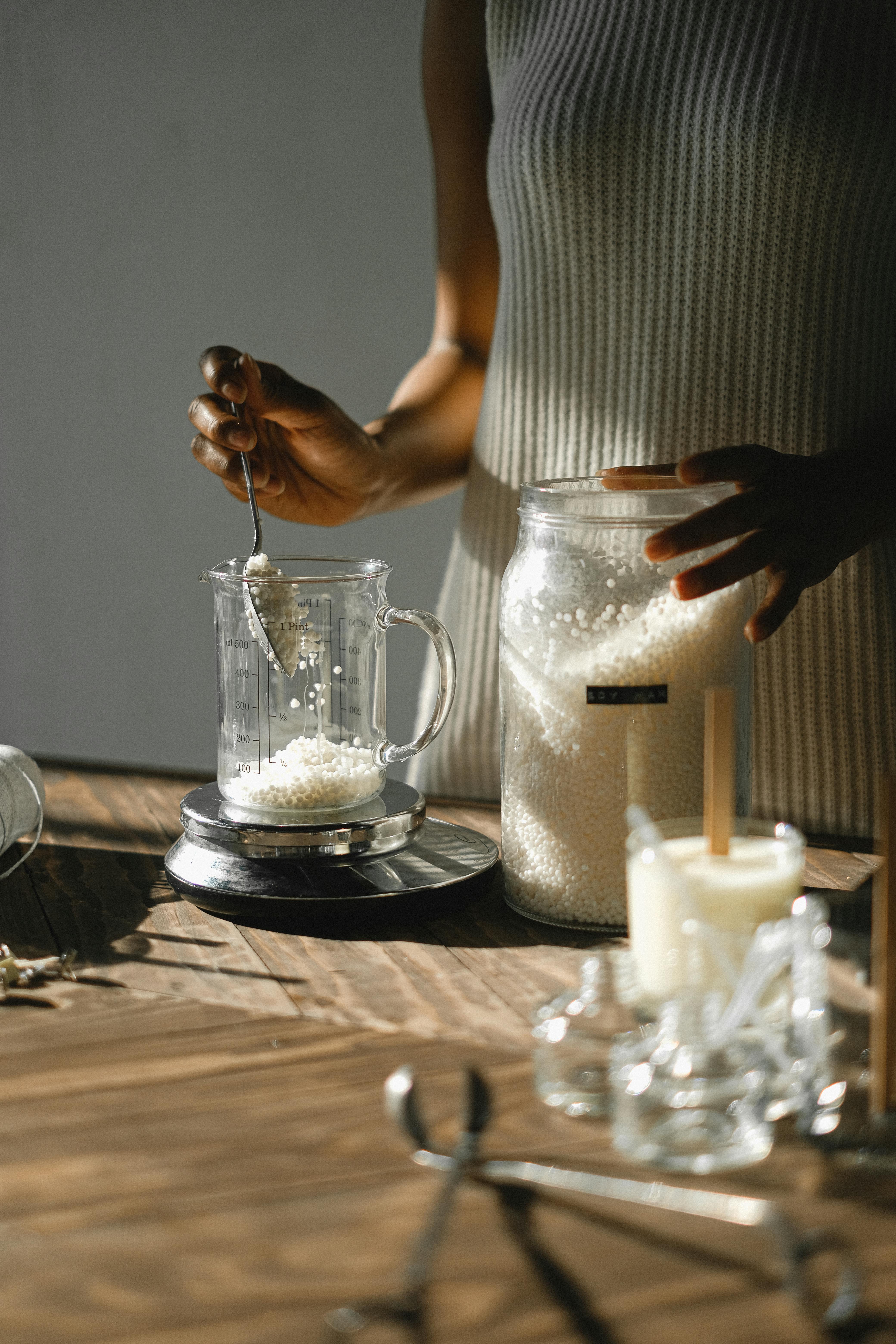 Crop black woman pouring wax into jug