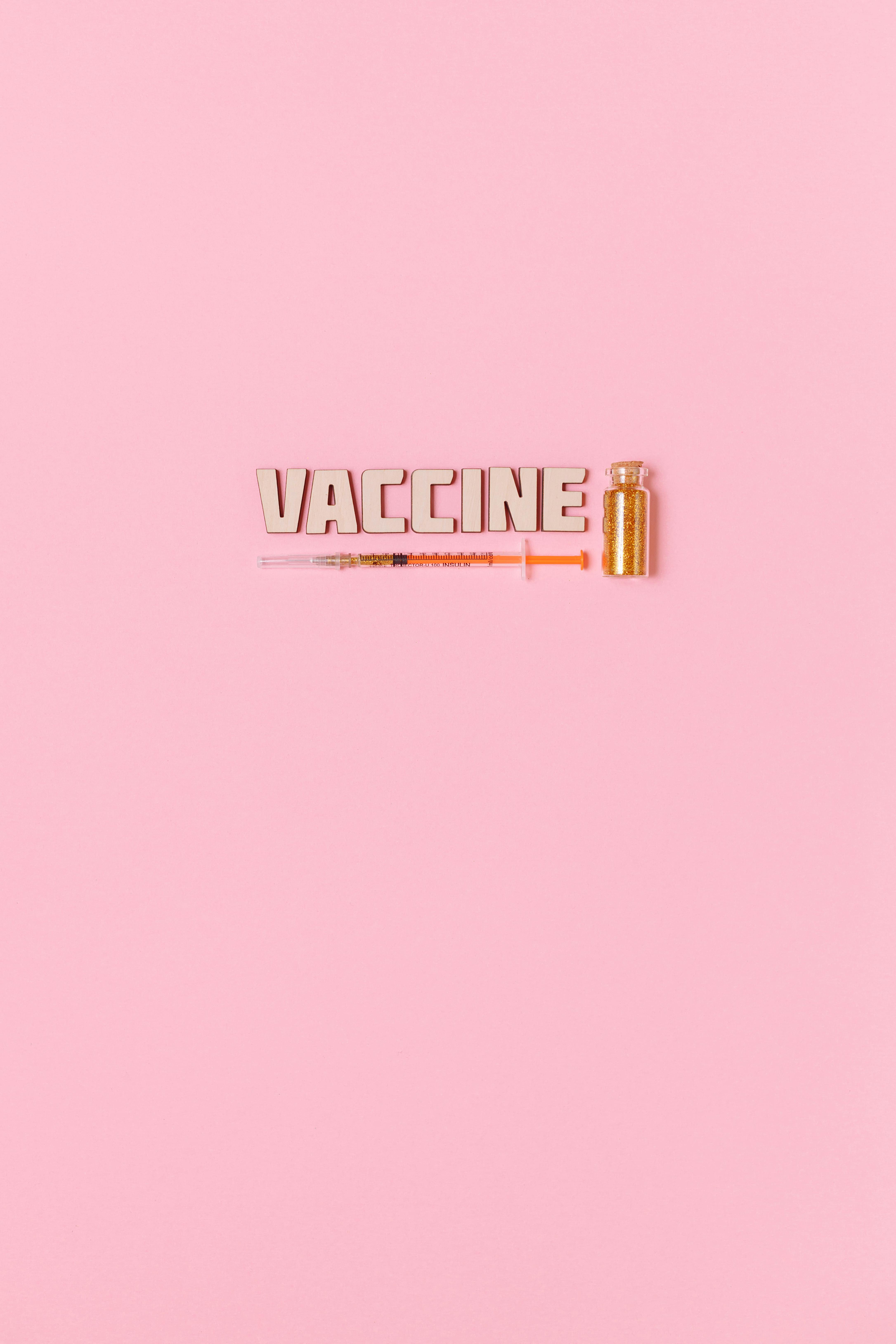 A Syringe and Vaccine Text on Pink Background