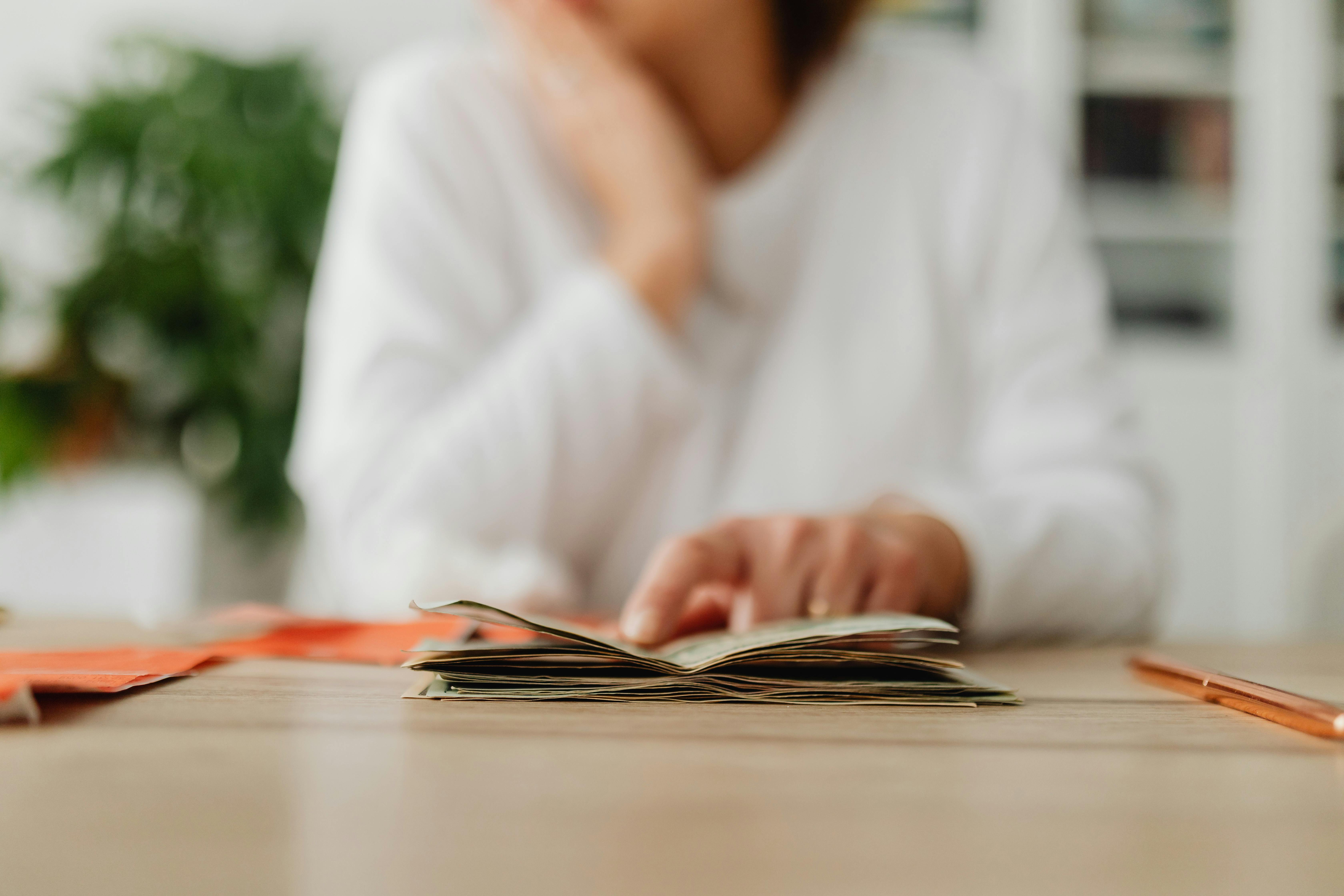 Woman Sitting Behind the Desk and Looking&nbsp;at Money and Receipts