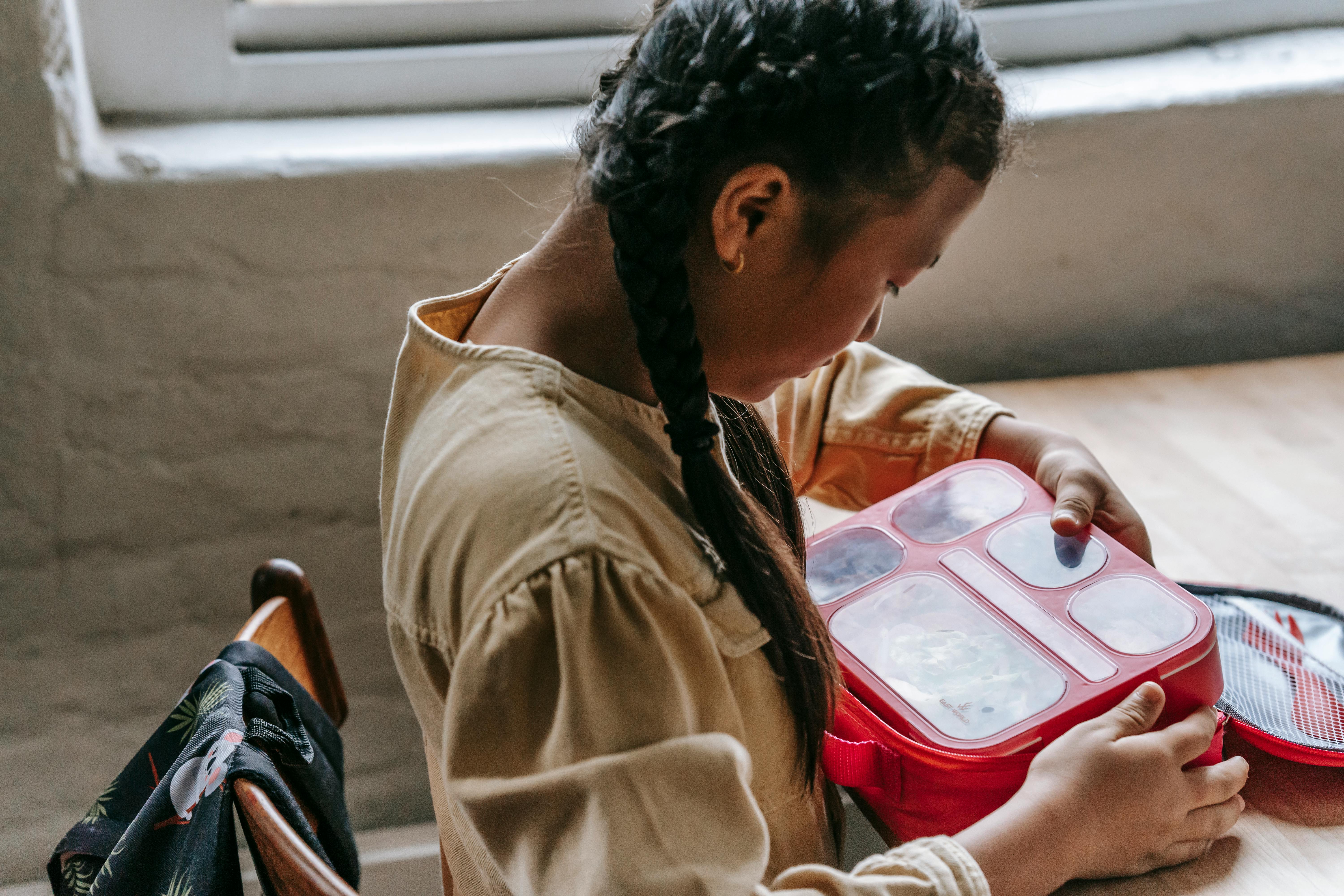 Ethnic teenage with lunch box in school