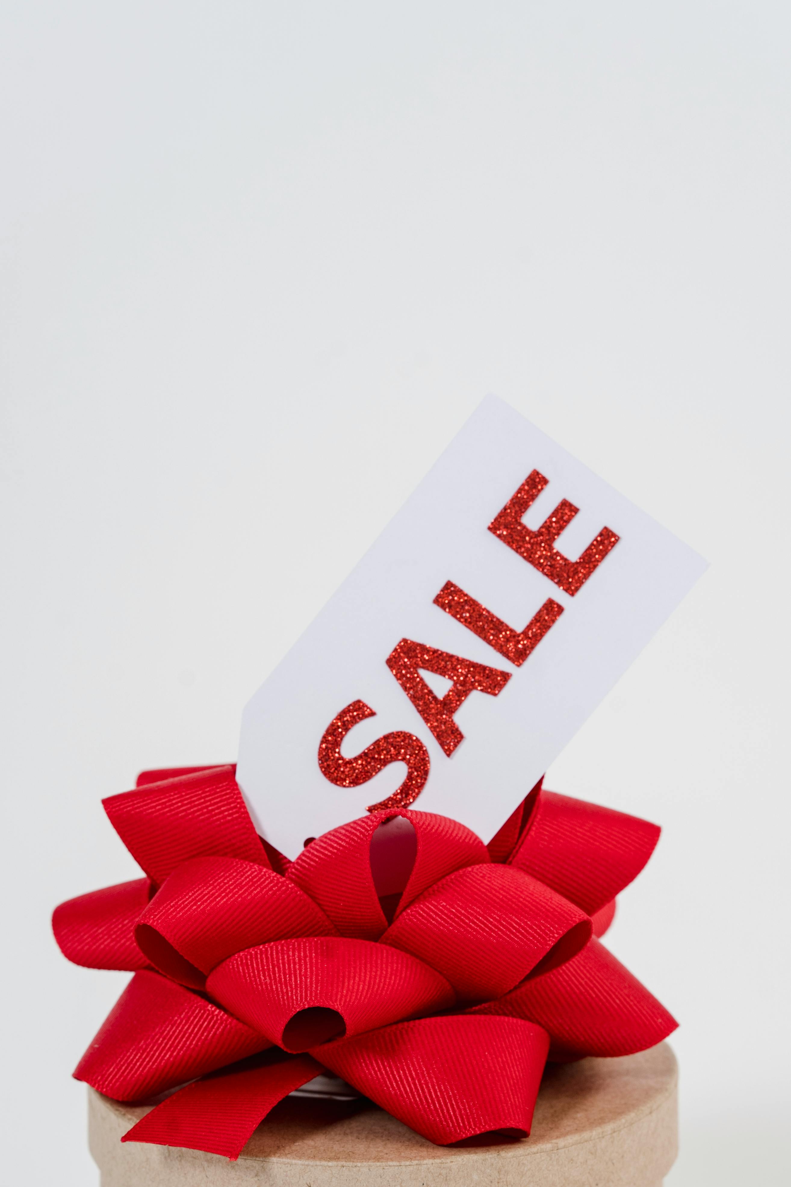 Close-Up Photo Of Red Ribbon With Sale Tag 