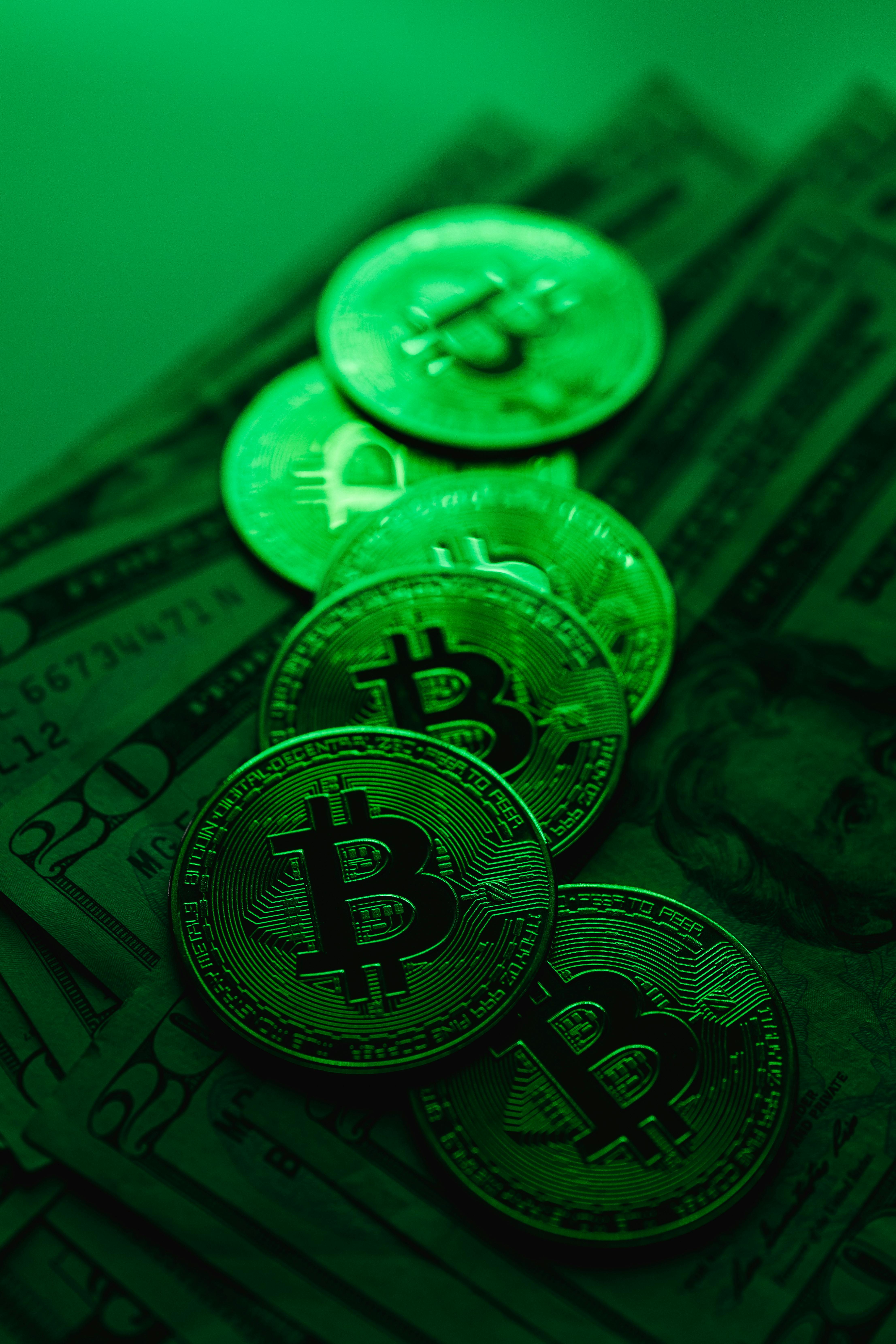 Bitcoins on Dollar Bills in Green Light