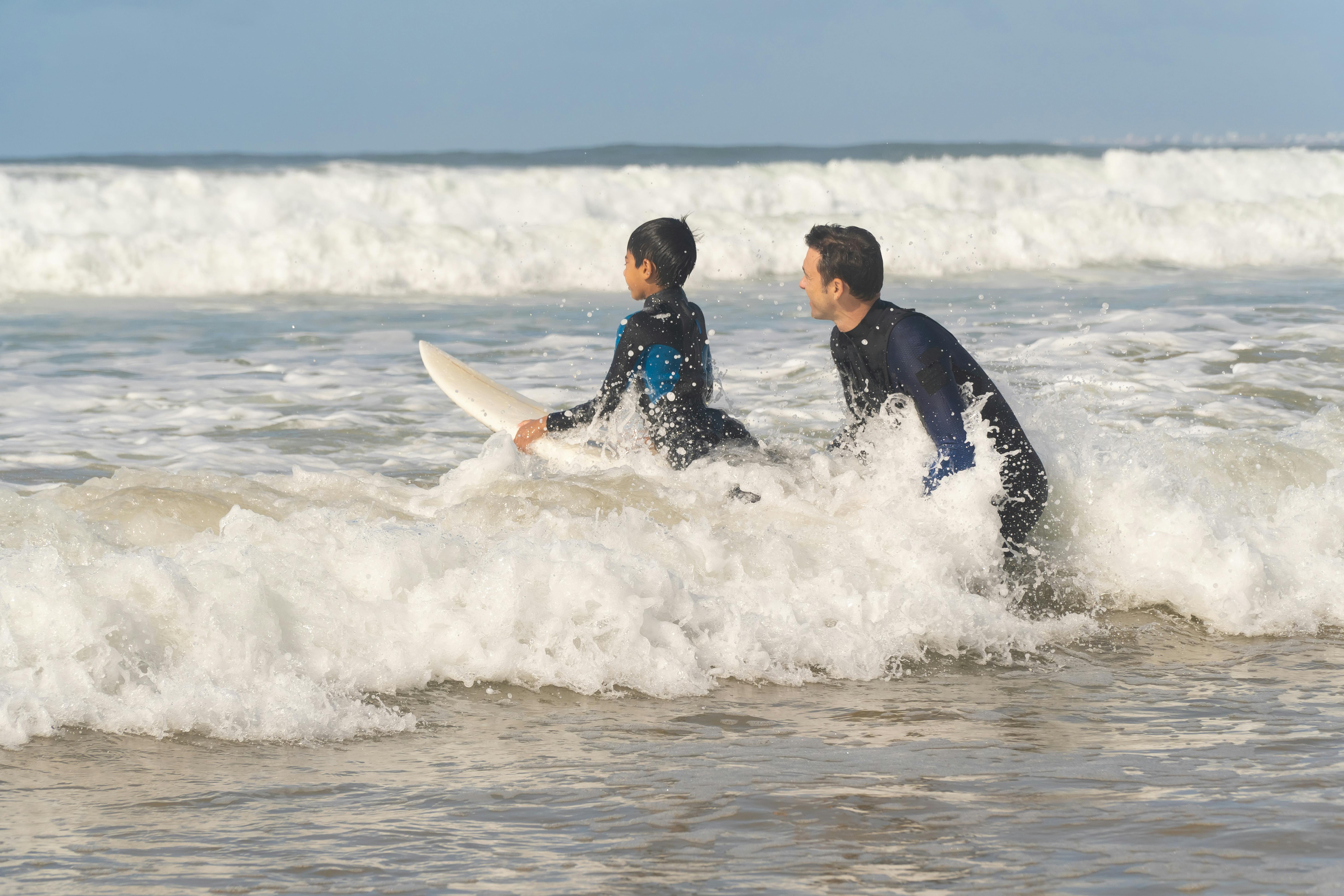 Man Guiding a Boy in Surfing