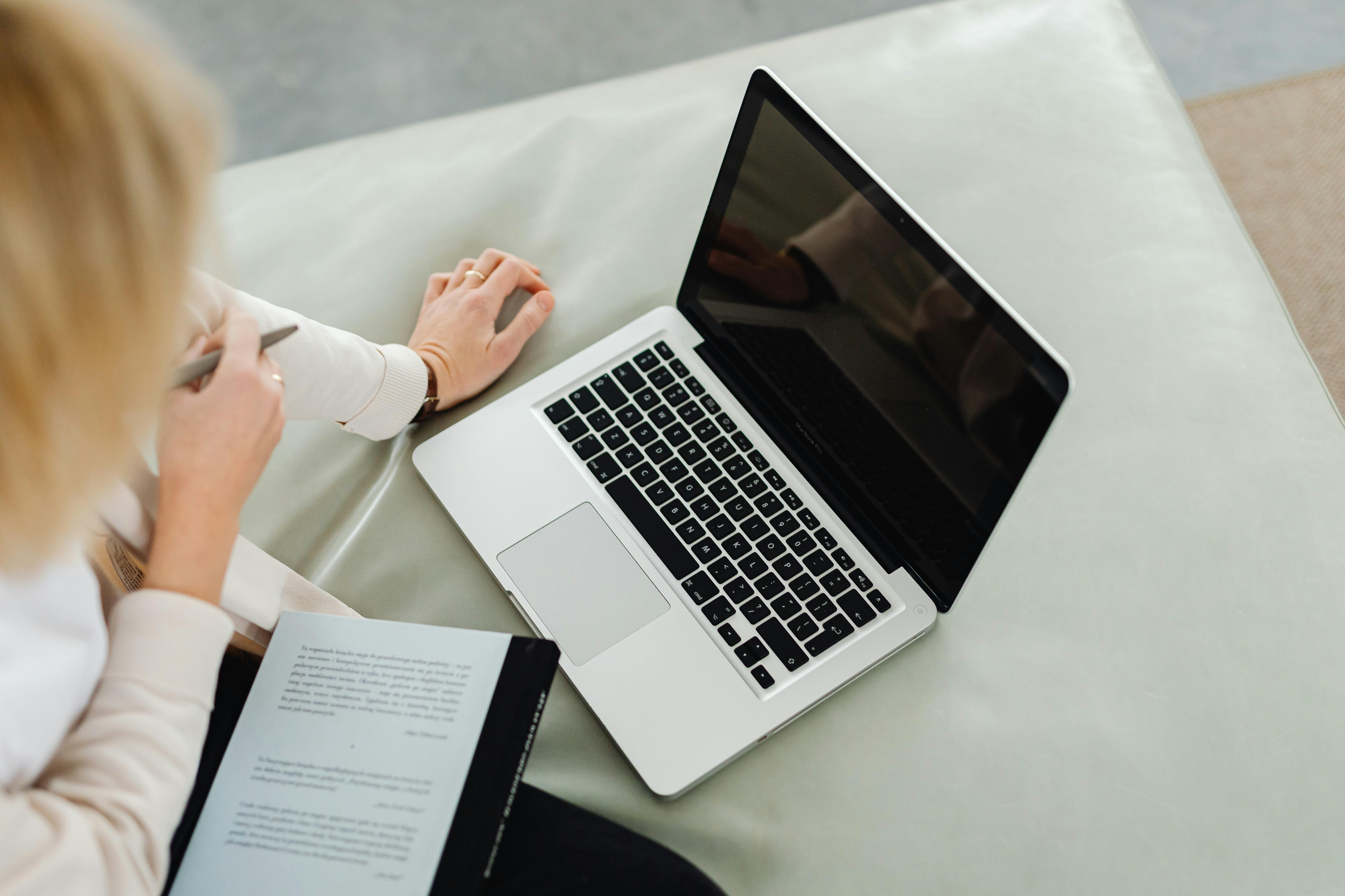 Photo of a Person's Hand Beside a Laptop