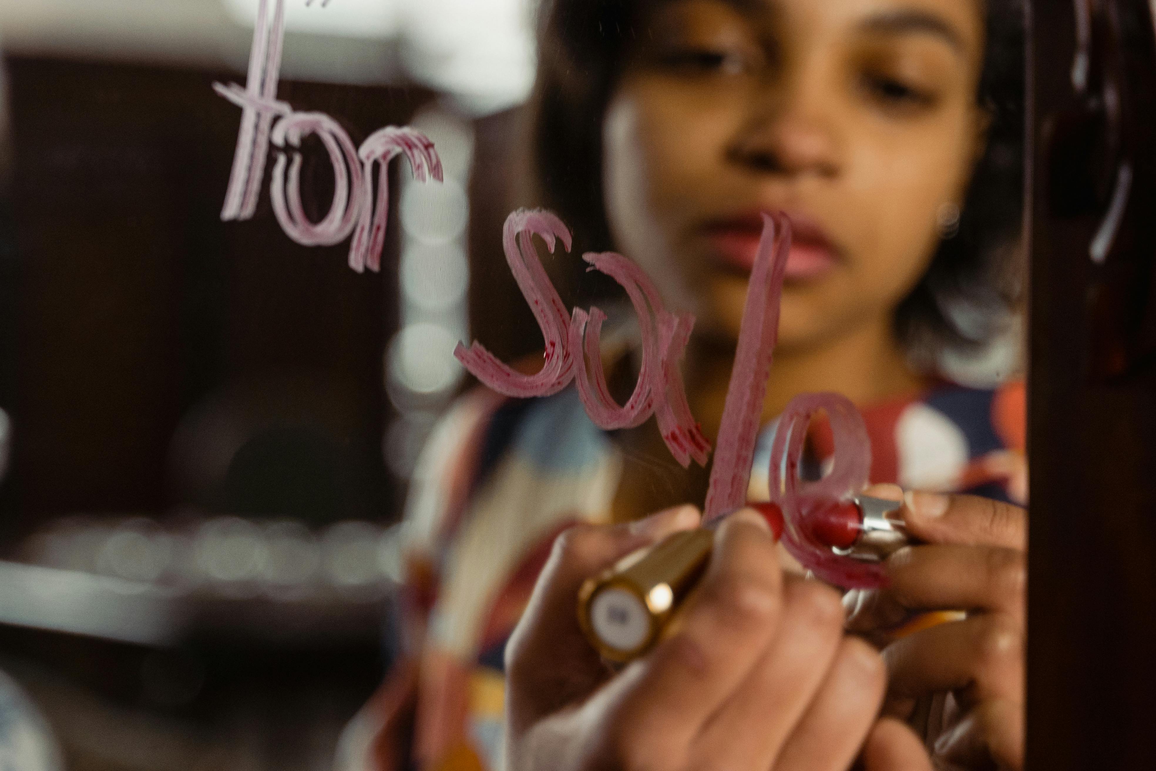 A Woman Writing on a Mirror Using a Lipstick