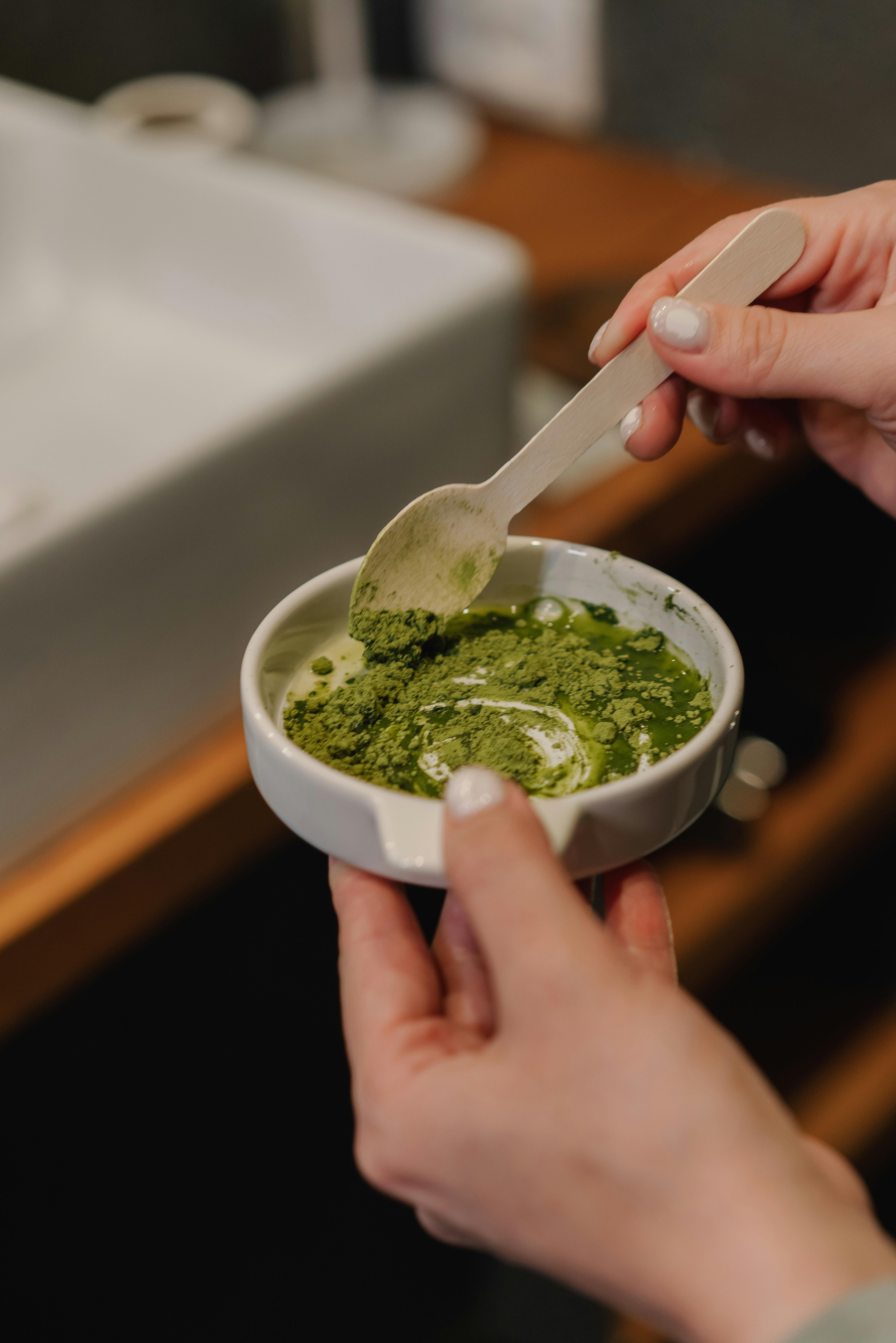 Person Holding White Ceramic Bowl With Green Powder