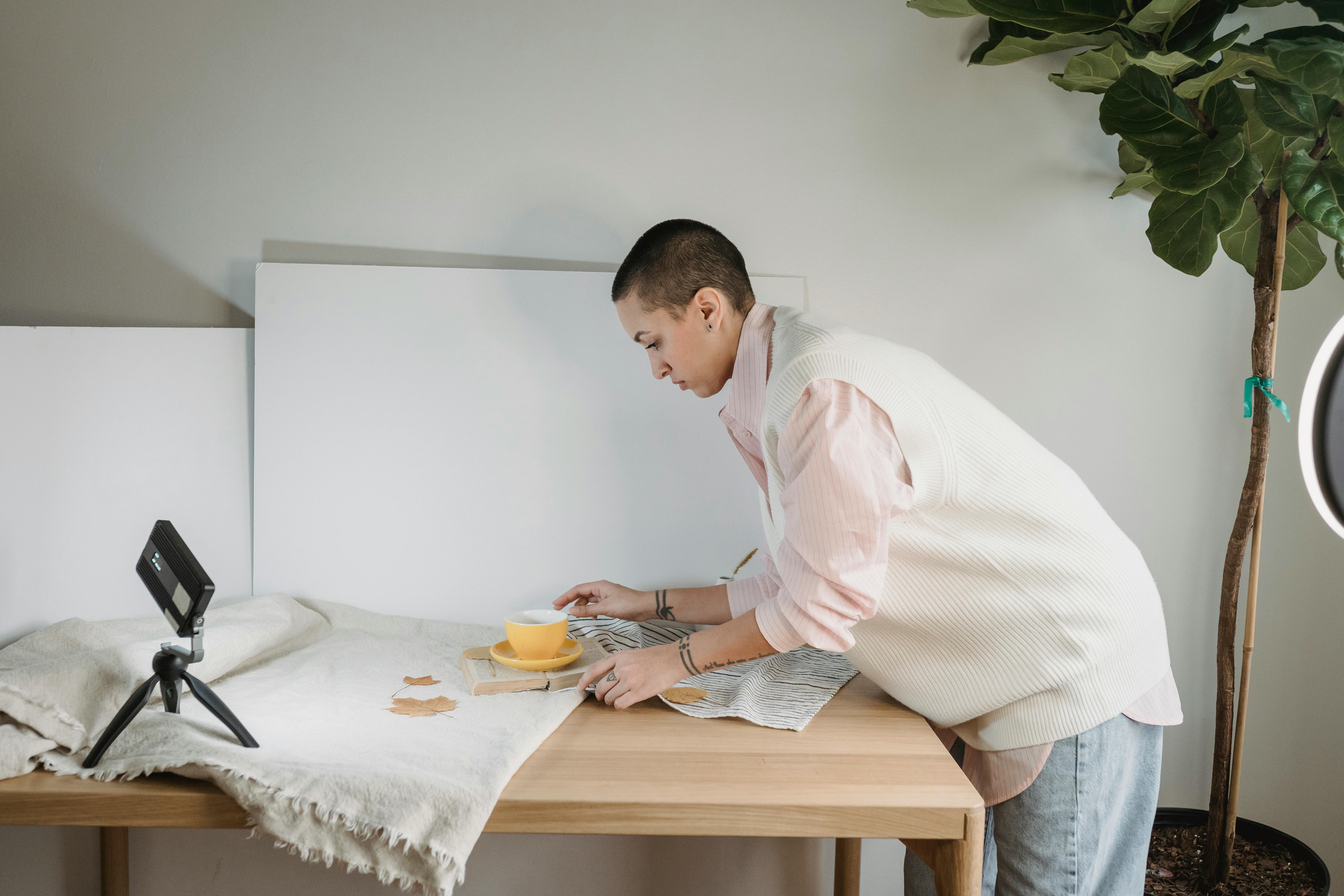 Photographer at table with cup and textiles at home