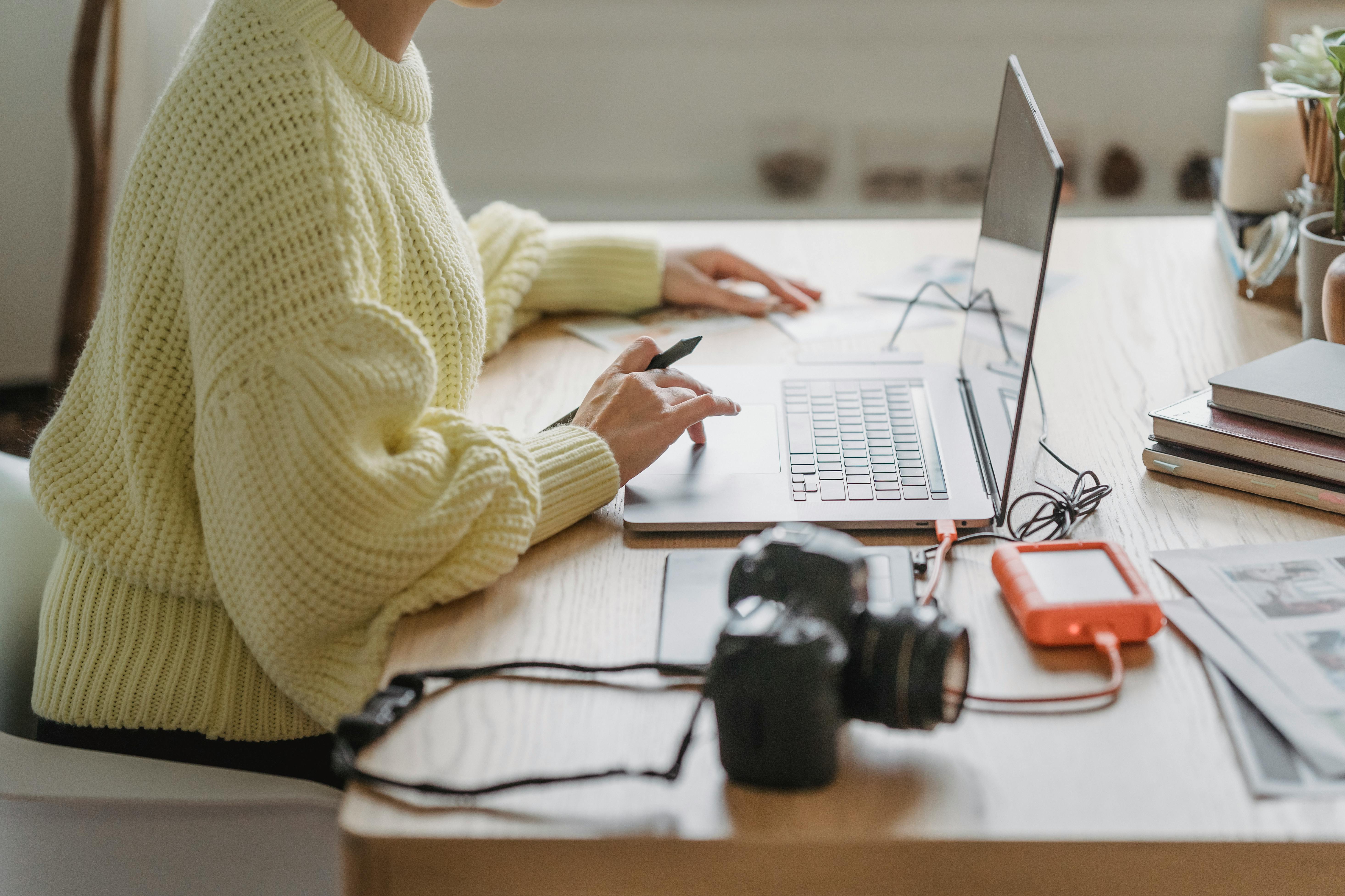 Anonymous photographer browsing laptop at table