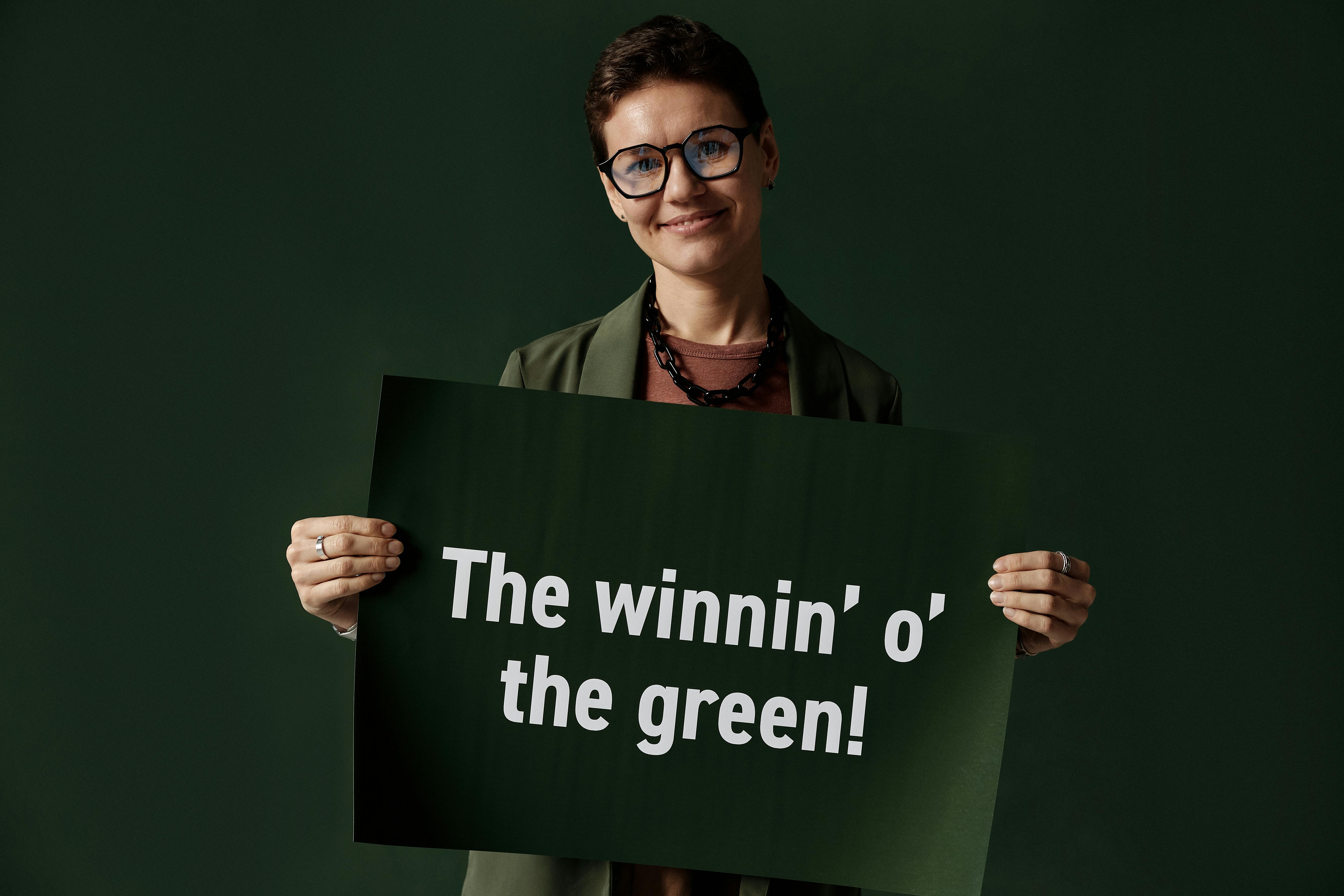 Woman Wearing Eyeglasses while Holding a Placard on Green Background