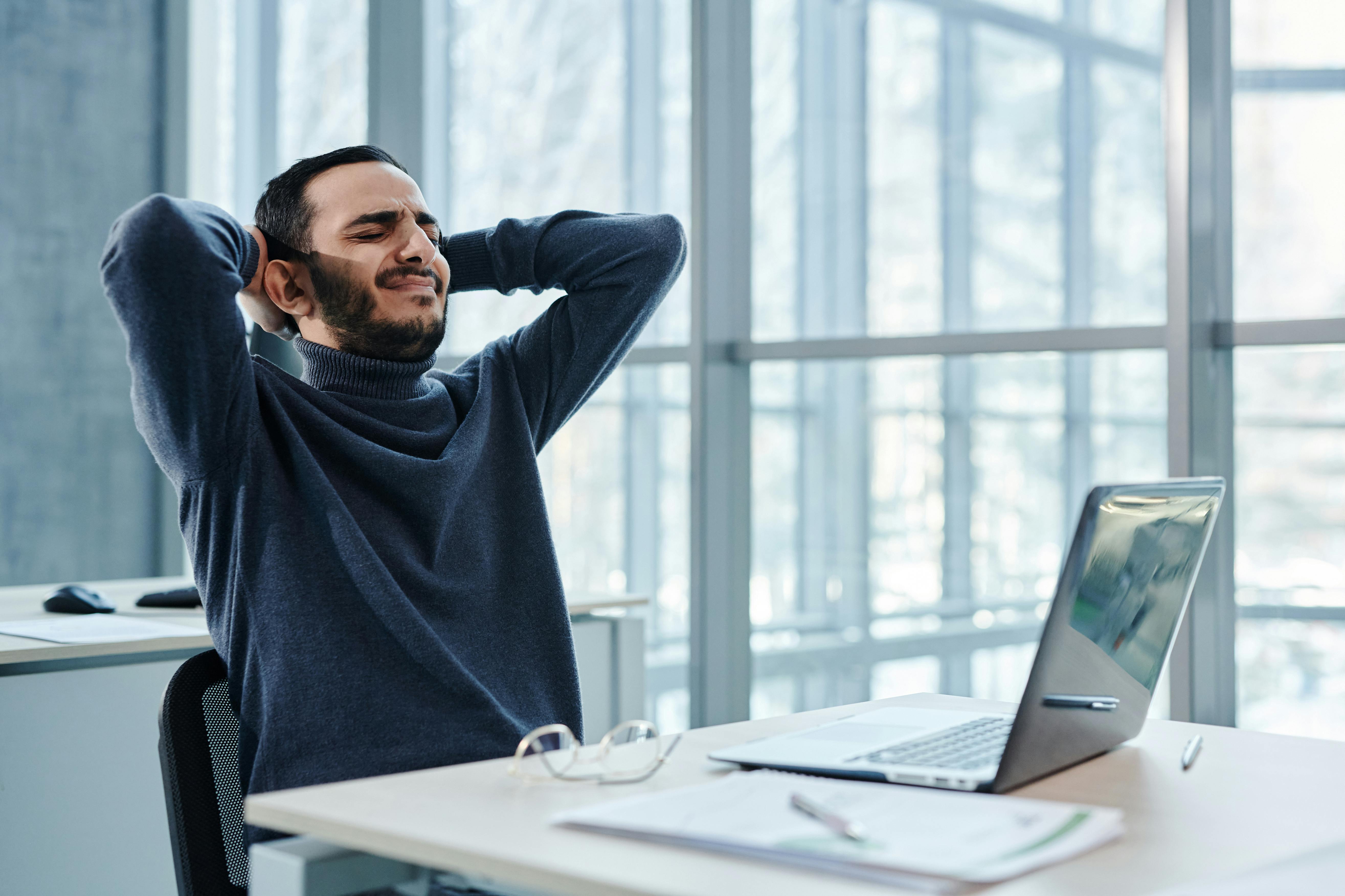 A Man in Black Sweater Using a Laptop