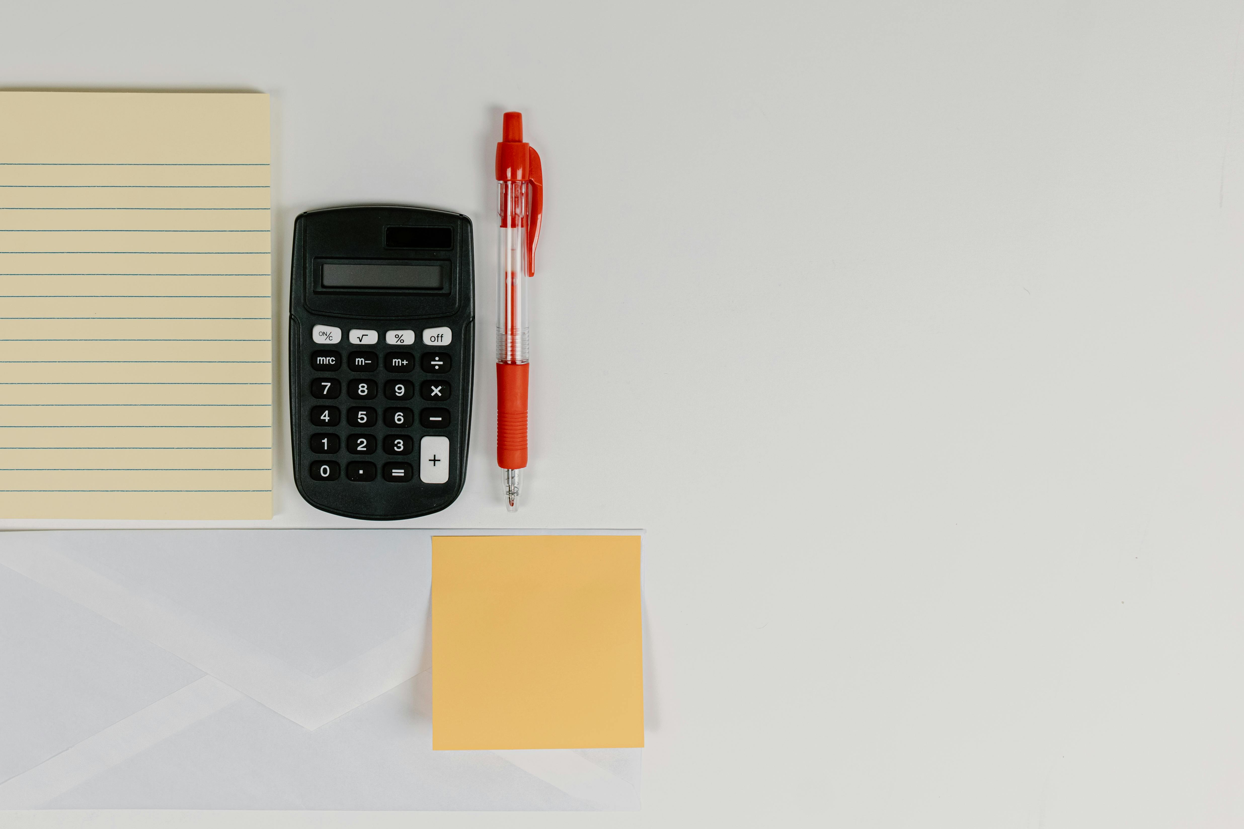 A Black Calculator beside a Ball Pen