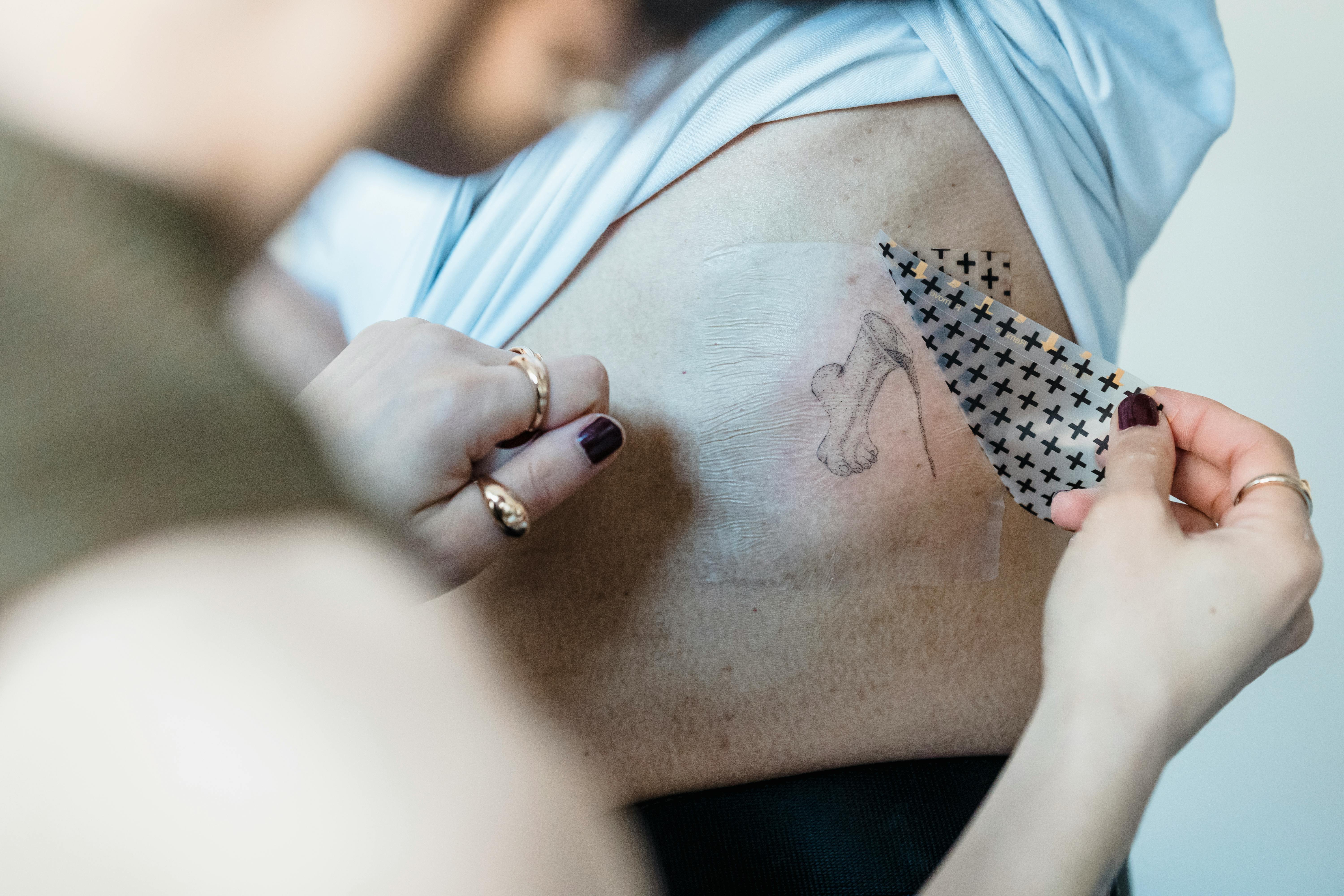 Close up of Womans Hands Applying a Temporary Tattoo to a Man