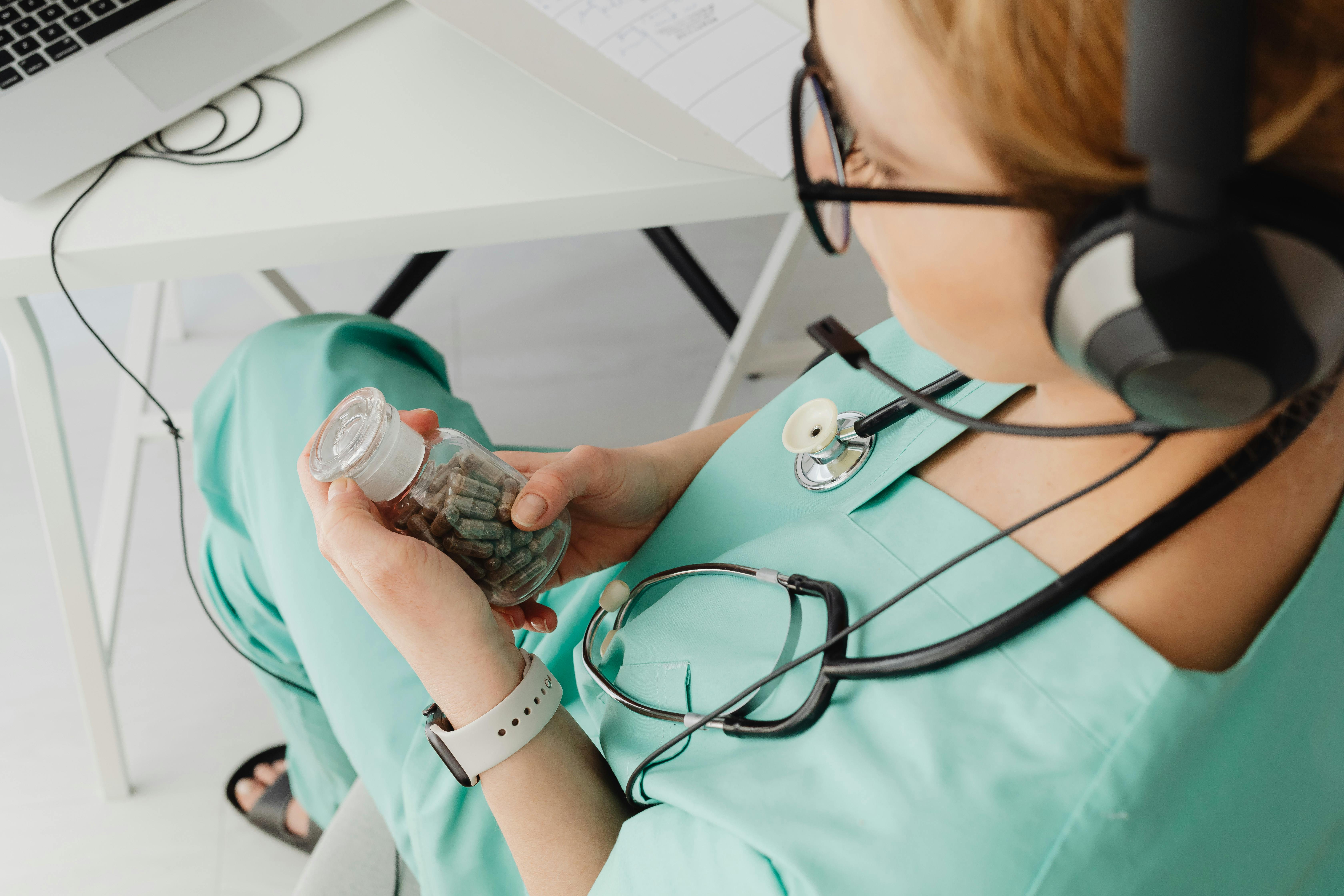Doctor Holding a Bottle with Pills and Doing an Online Meeting with a Patient