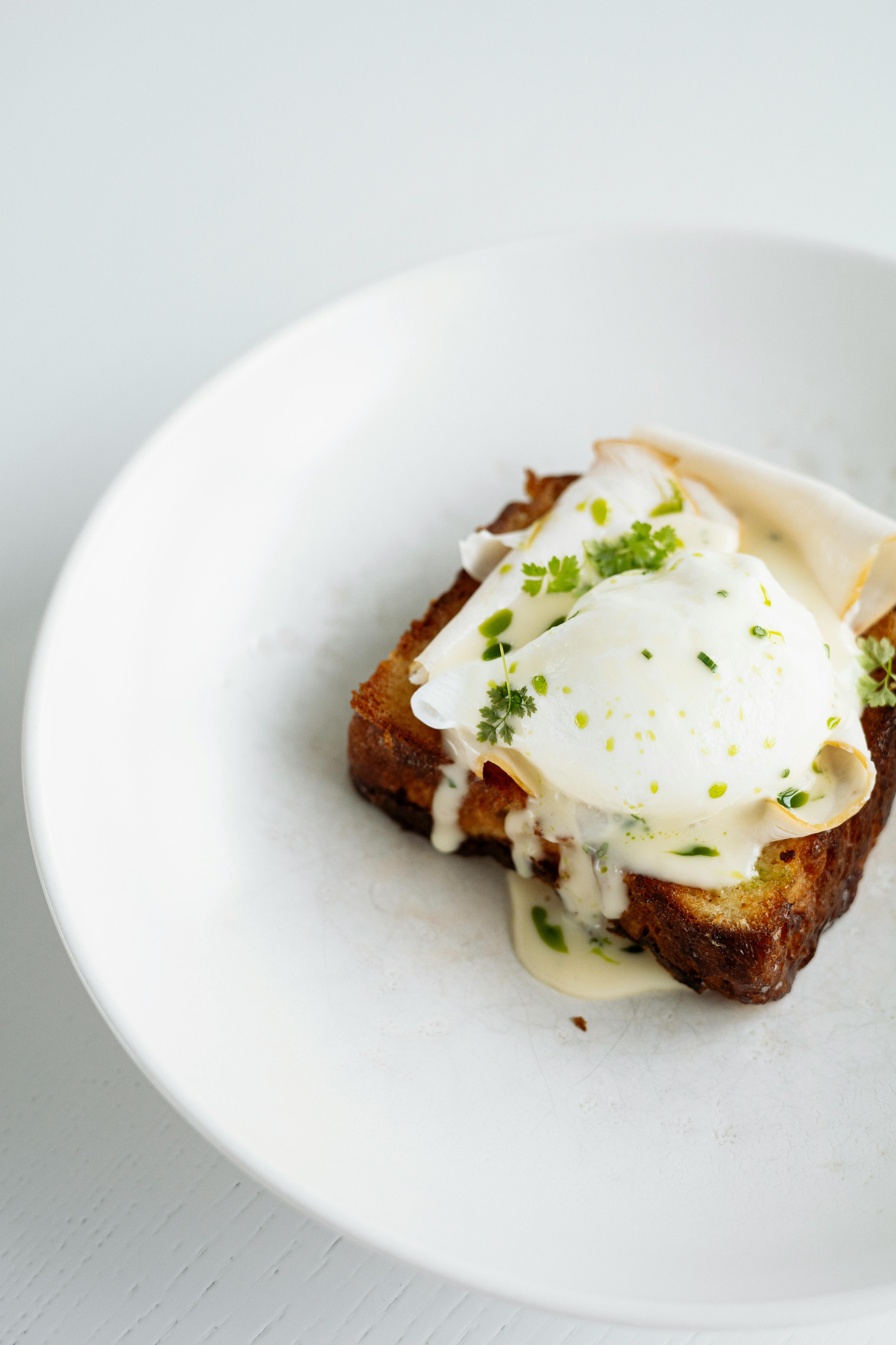 Brown Bread With White Cream and Green Vegetable on White Ceramic Plate