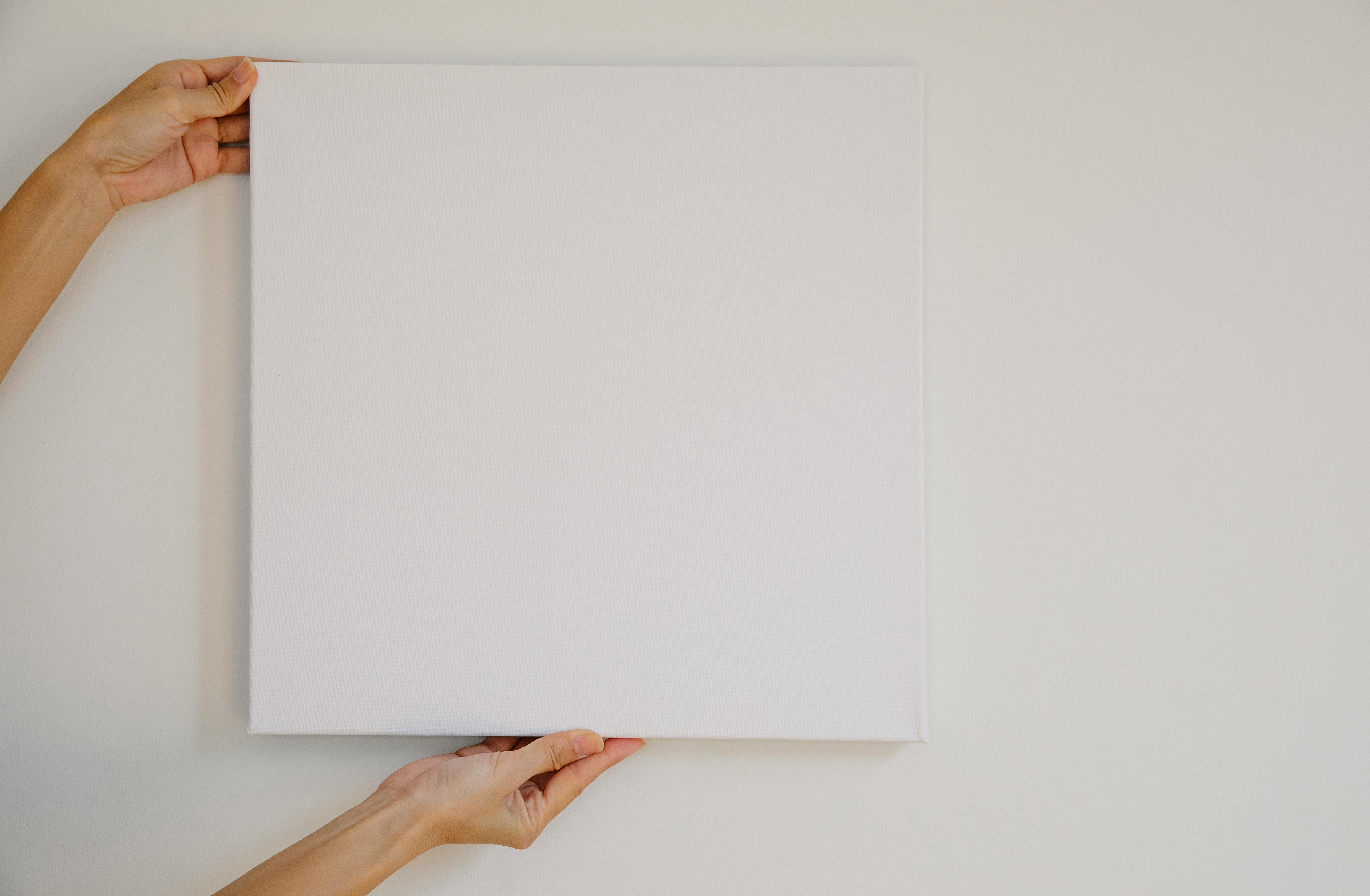 Unrecognizable female demonstrating empty poster of square shape during advertisement campaign against gray wall