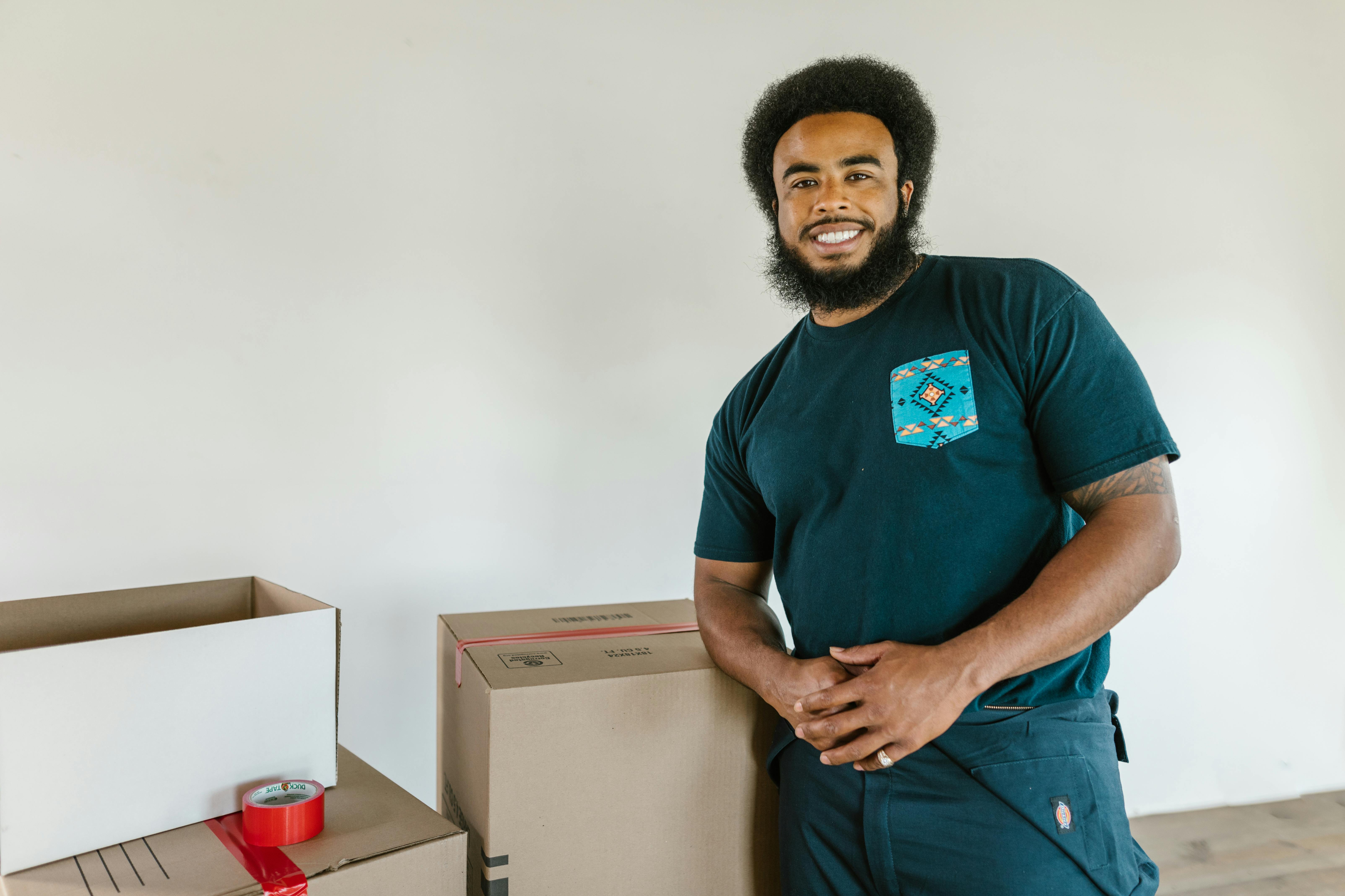 Smiling Man Standing Next to Moving Boxes 