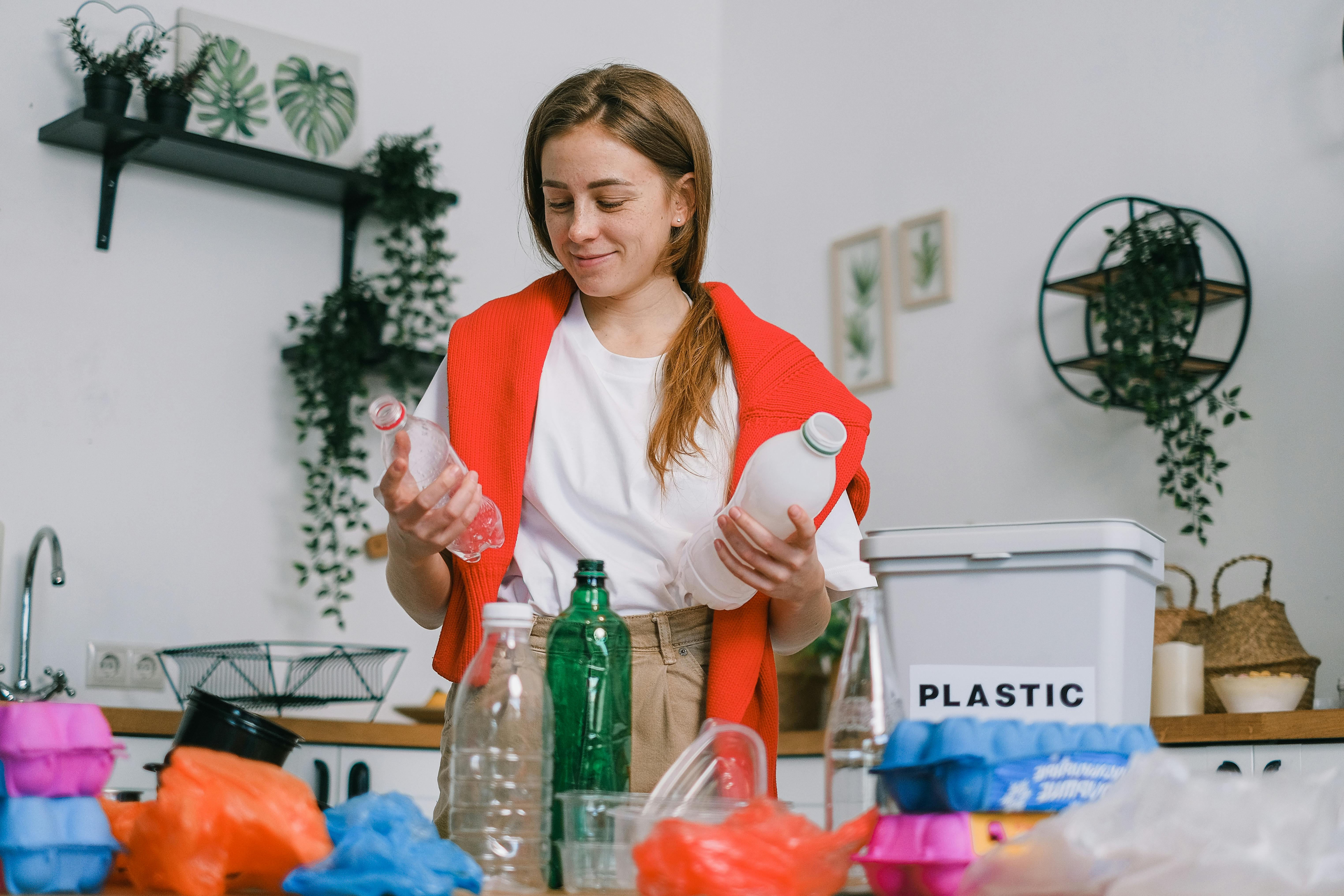 Cheerful female holding plastic bottles in kitchen