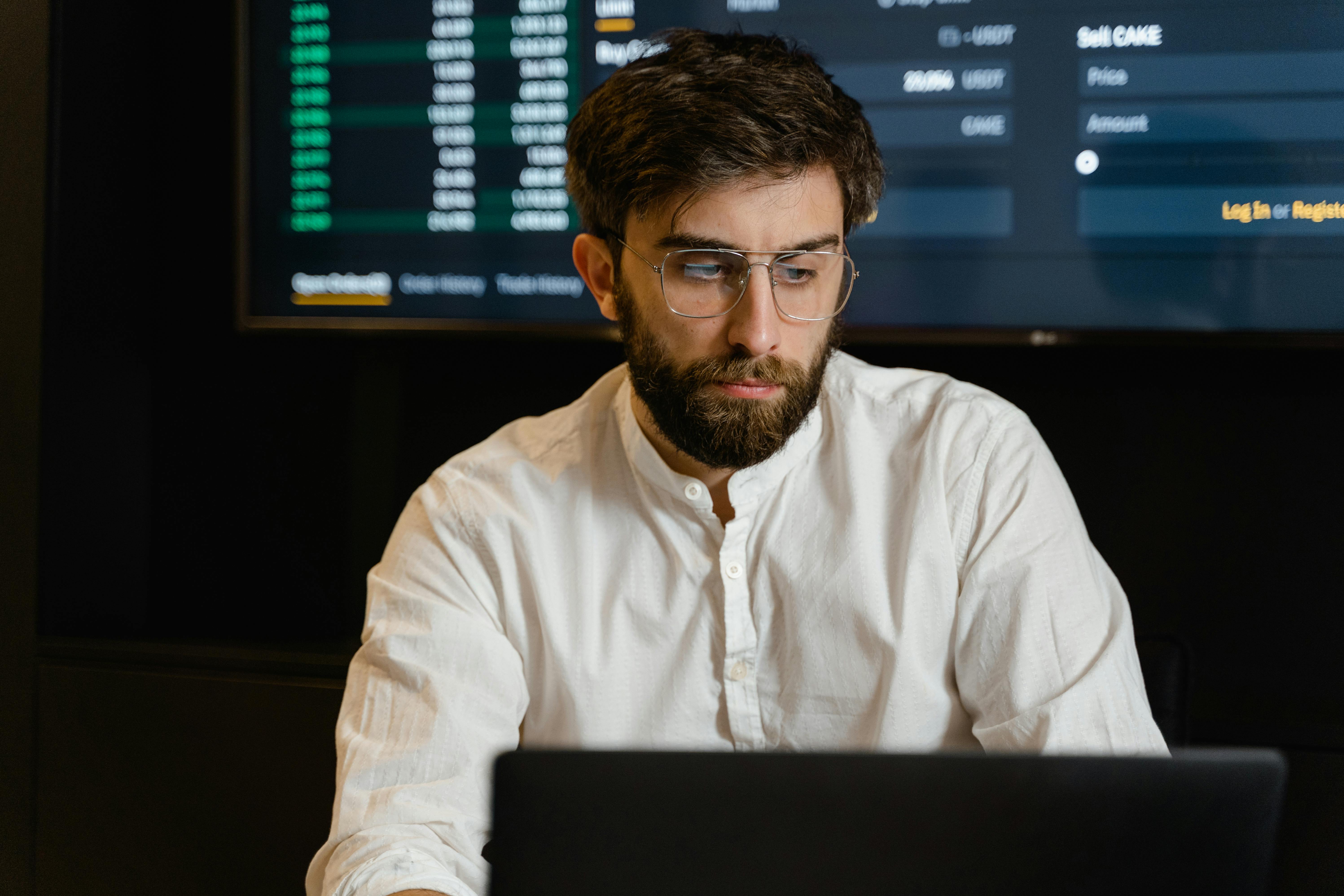 Man in White Dress Shirt Wearing Eyeglasses Using A Laptop