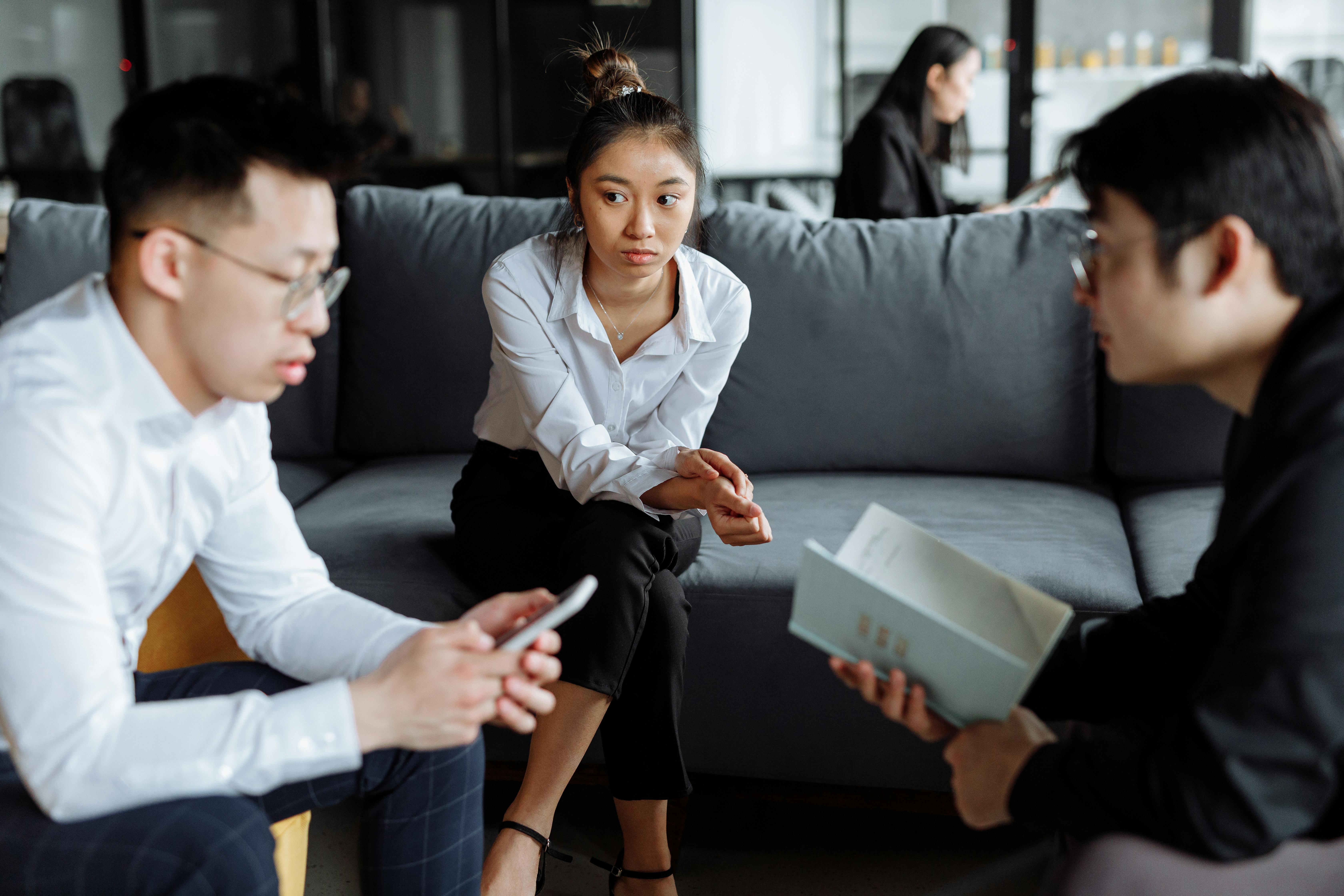 Man in White Long Sleeves Using a Smartphone in front of His Colleagues
