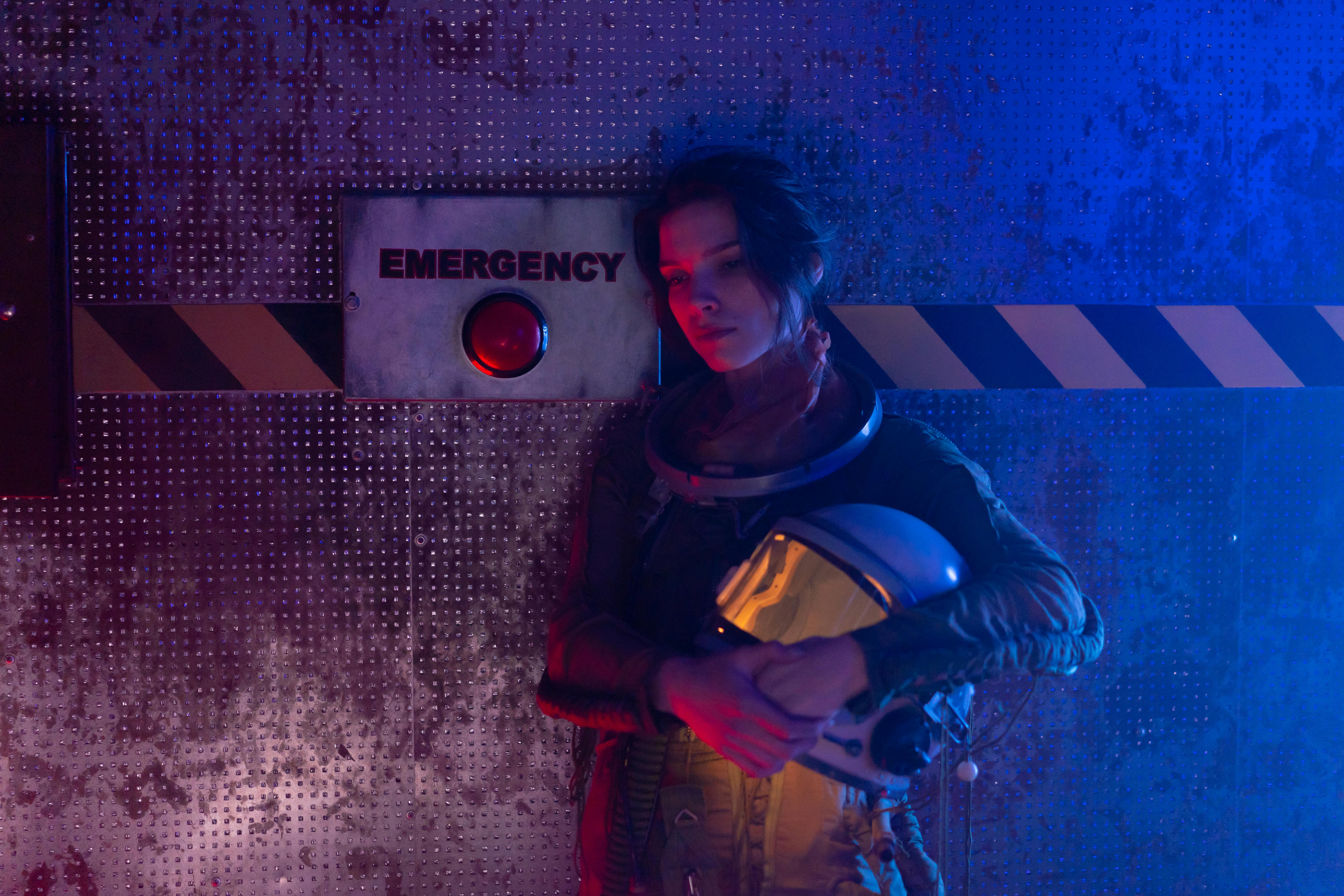 Woman in Black and Red Jacket Standing Beside Blue and White Wall