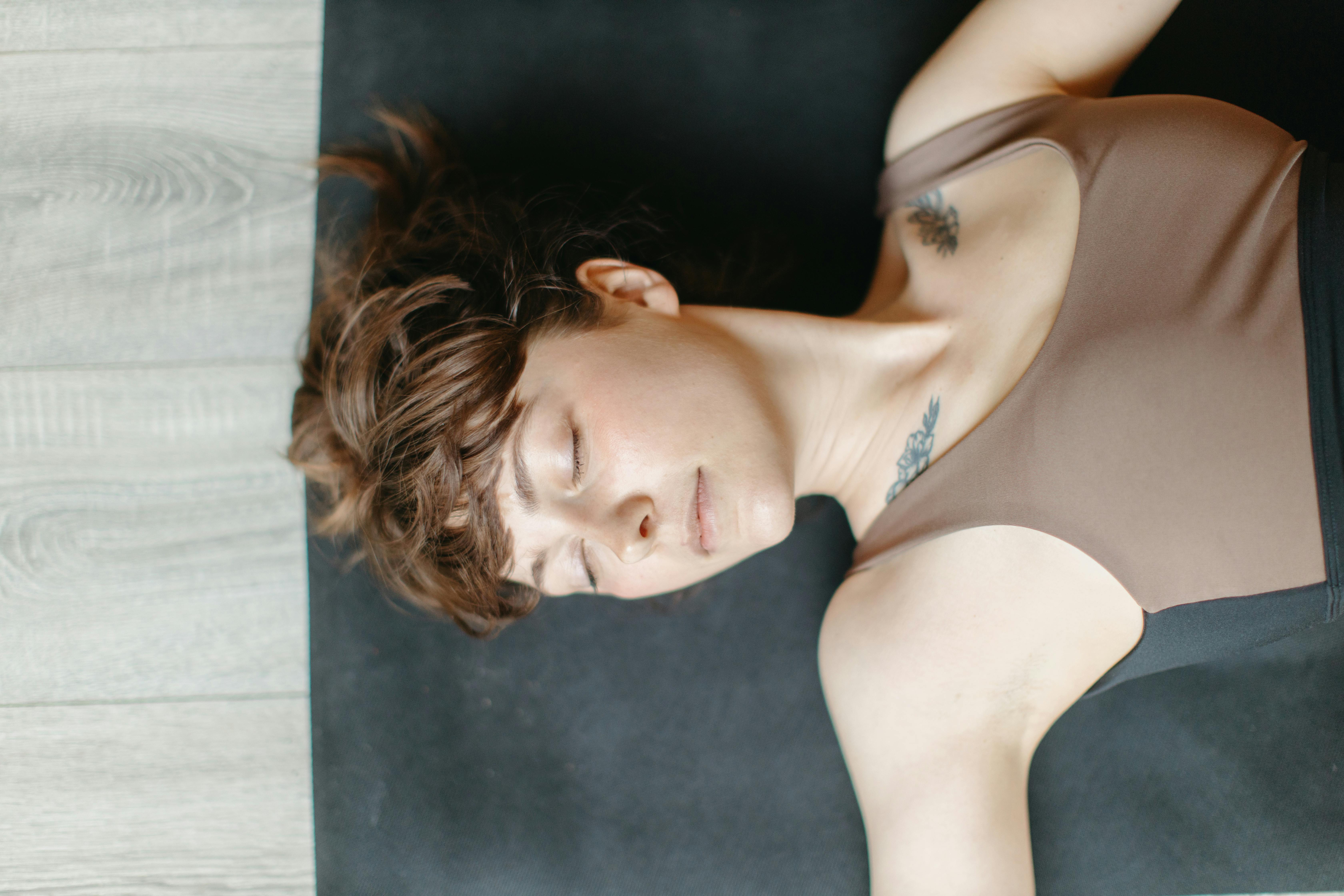 A Woman Wearing Tank Top Lying on the Yoga Mat