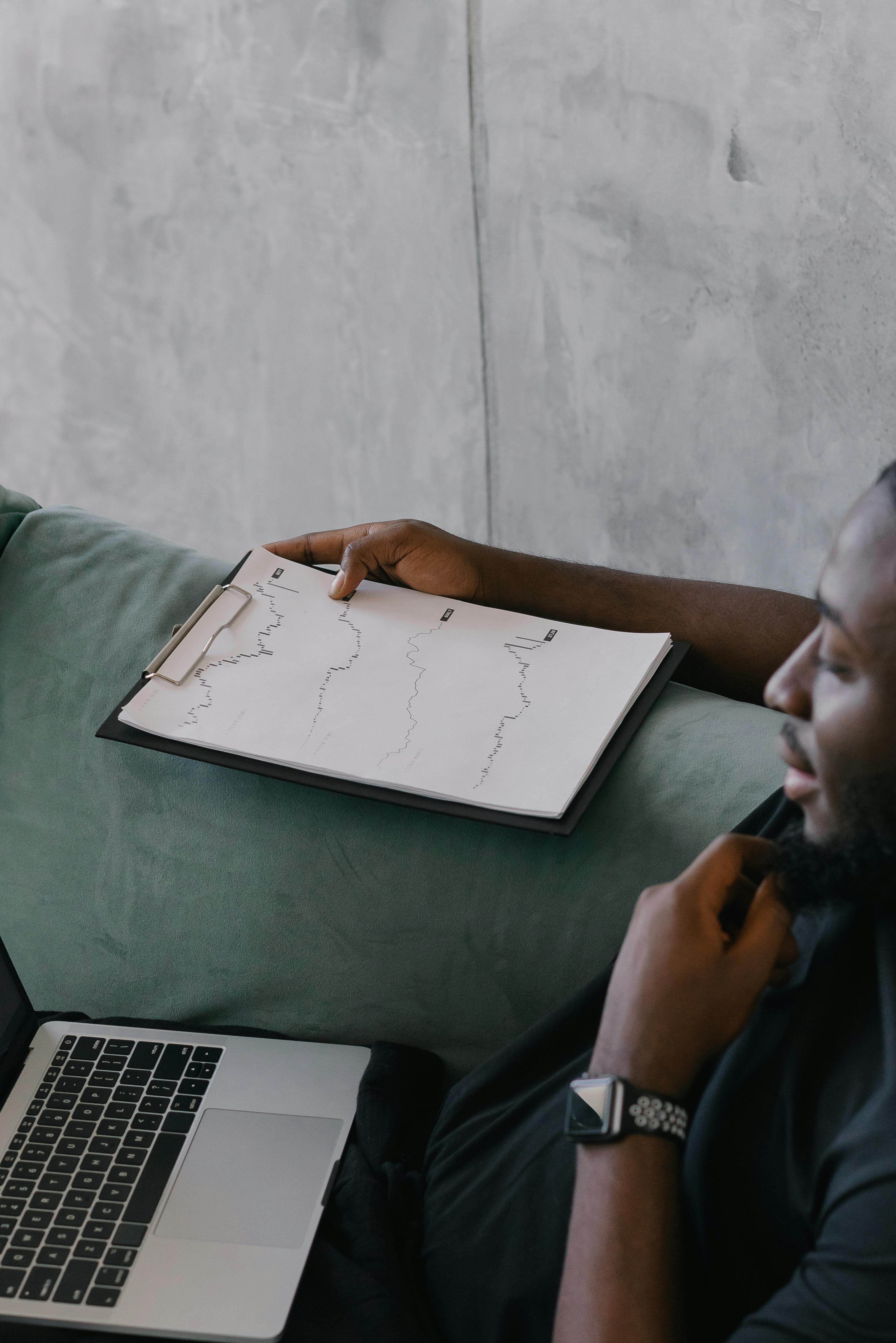 Man Sitting on Couch Holding a Clipboard 