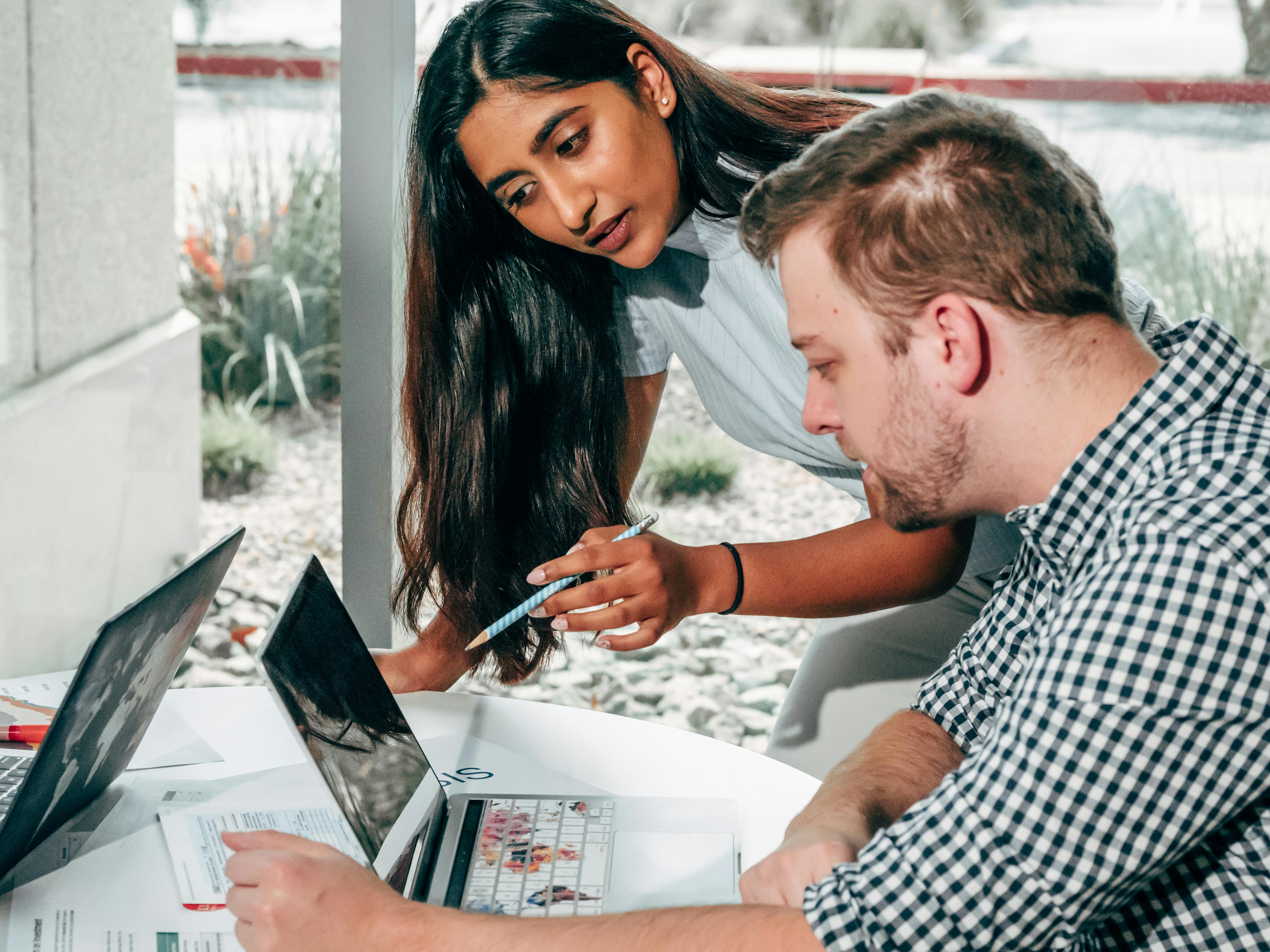 A Man and Woman Having Conversation while Looking at the Laptop