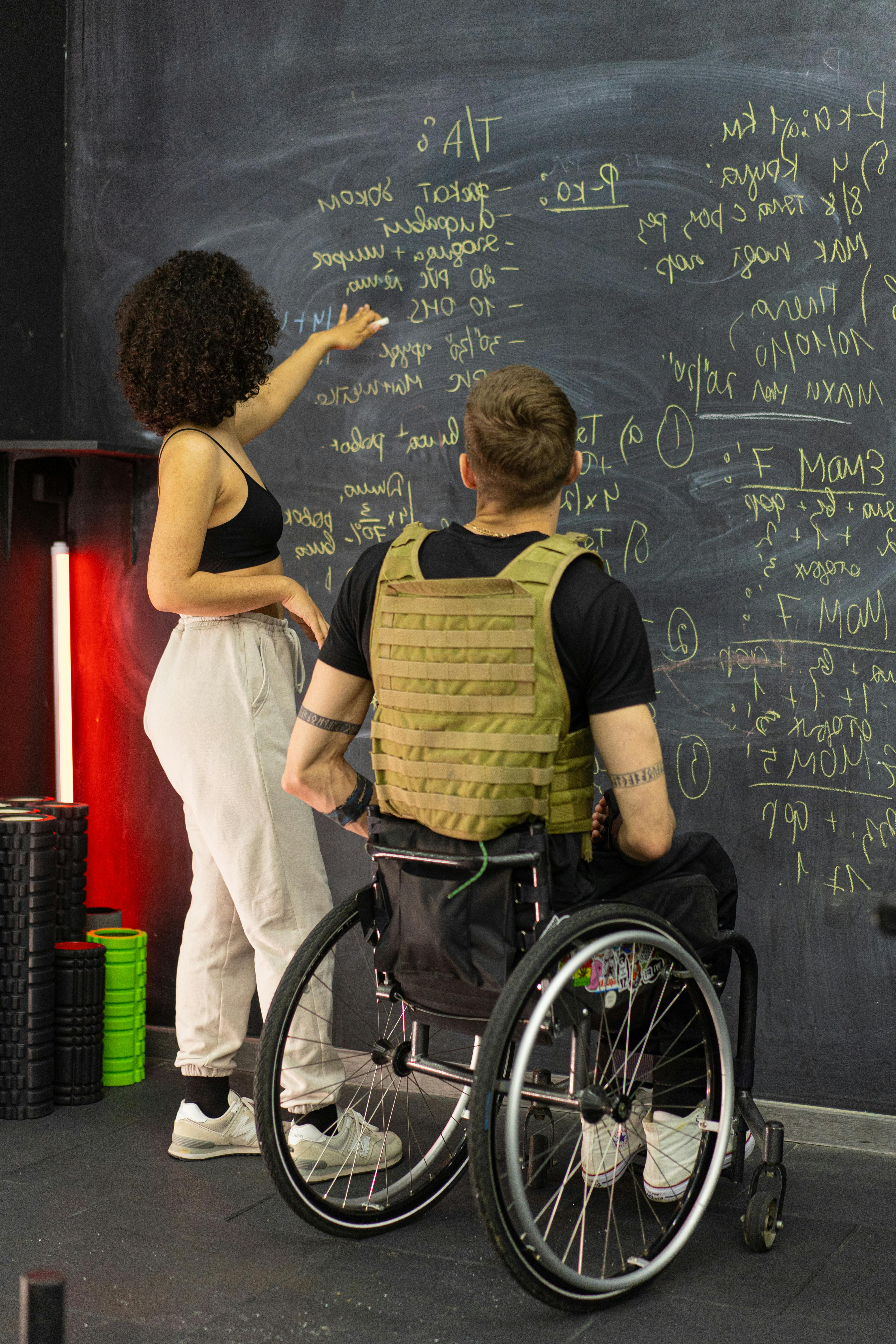 Woman with Man in Wheelchair by Blackboard