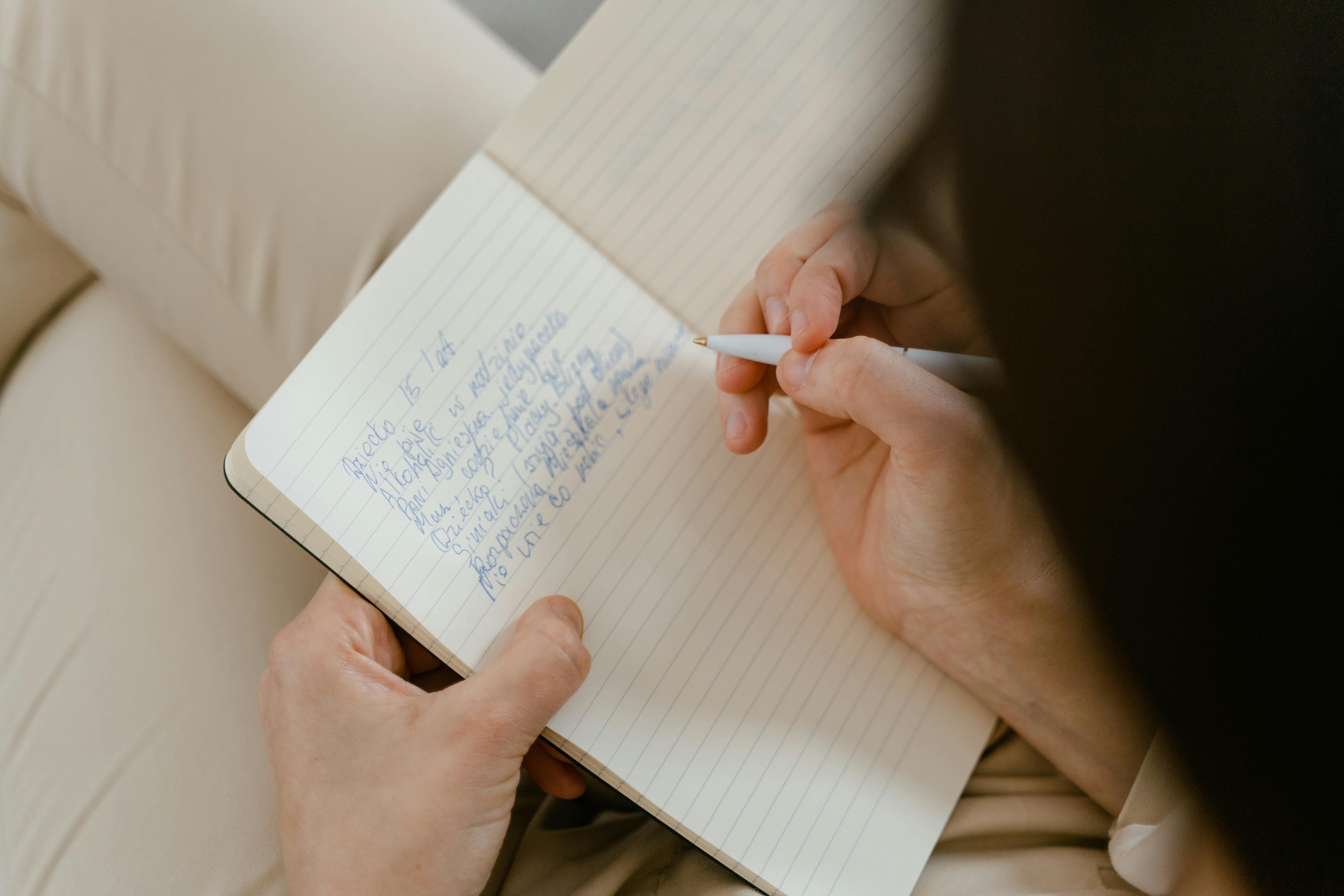 A Person Writing on a Notebook