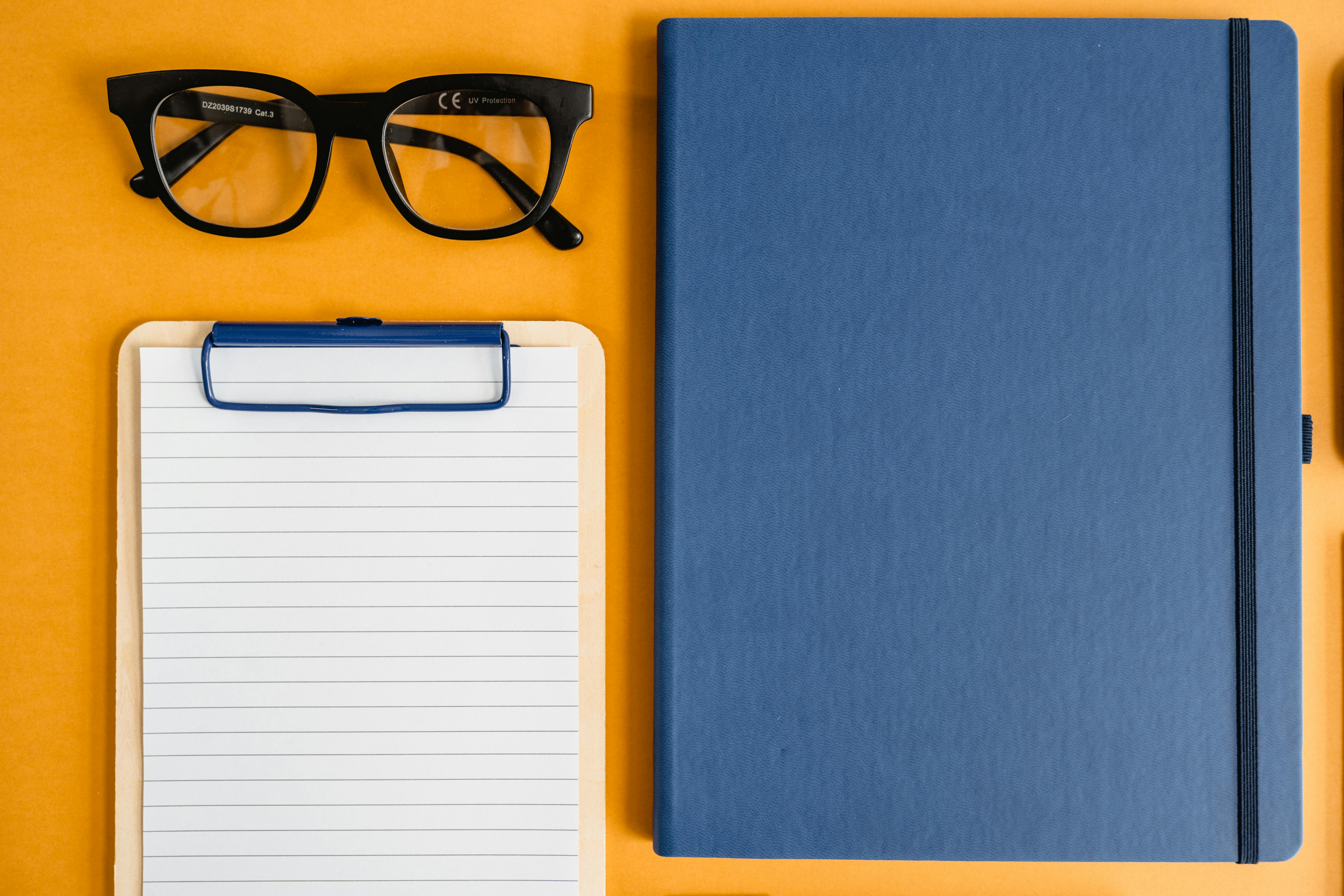 Glasses Lying next to Clipboard and Journal