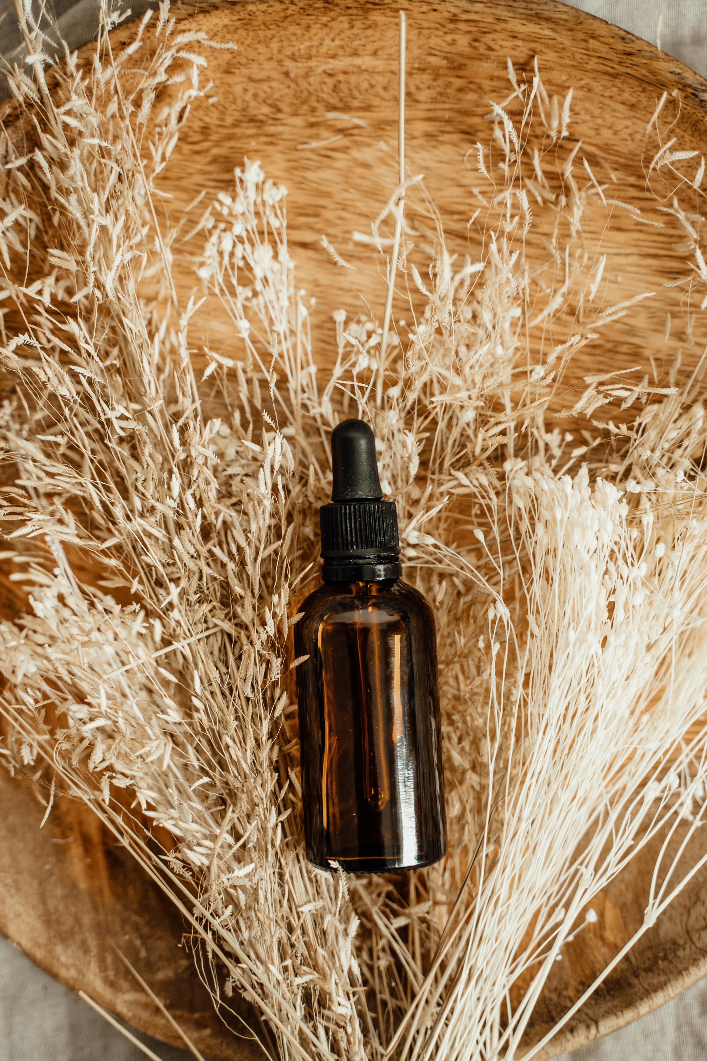 Brown Glass Bottle with a Pipette Lying on Dry Grass 