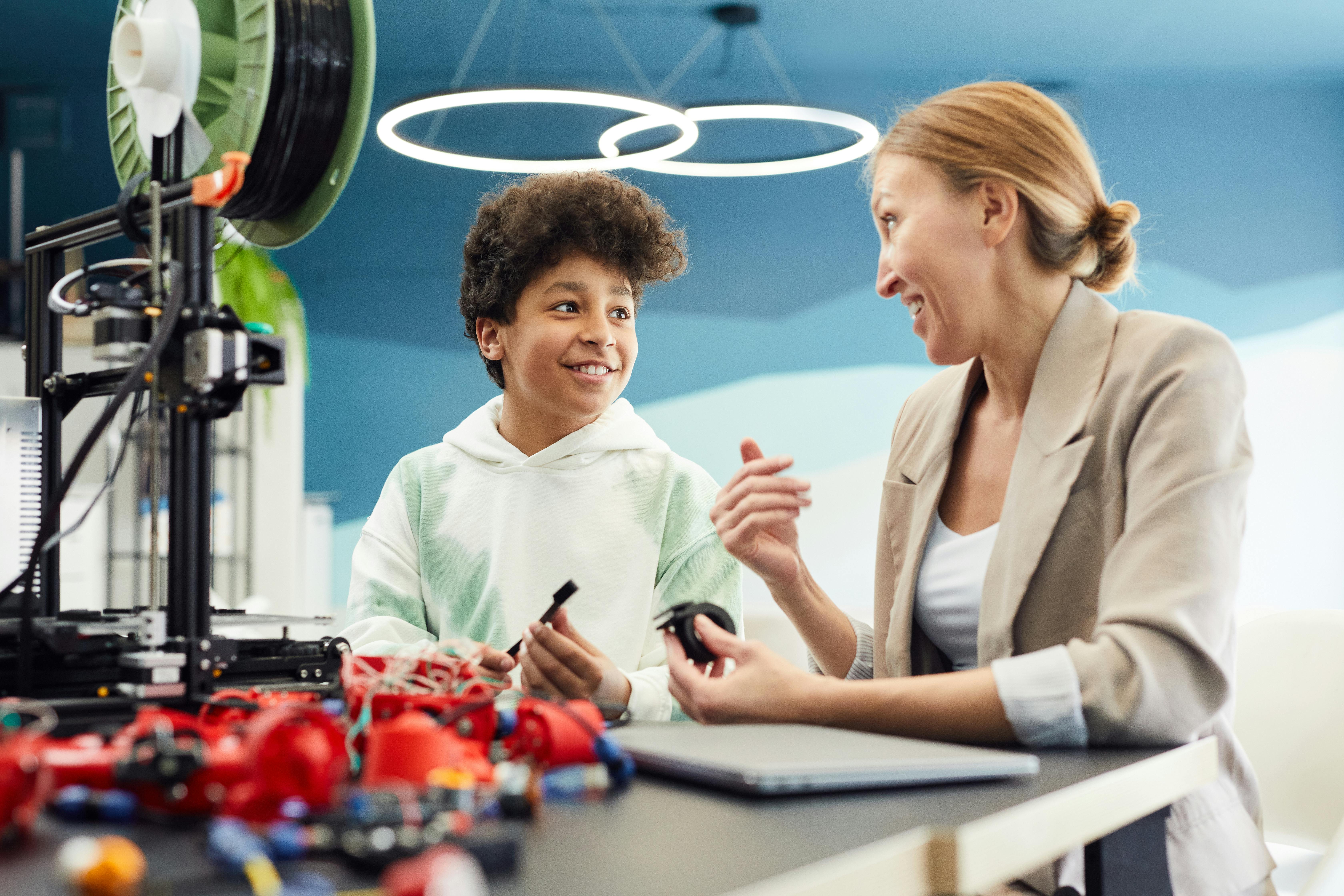 Cheerful boy working with woman on engineering project