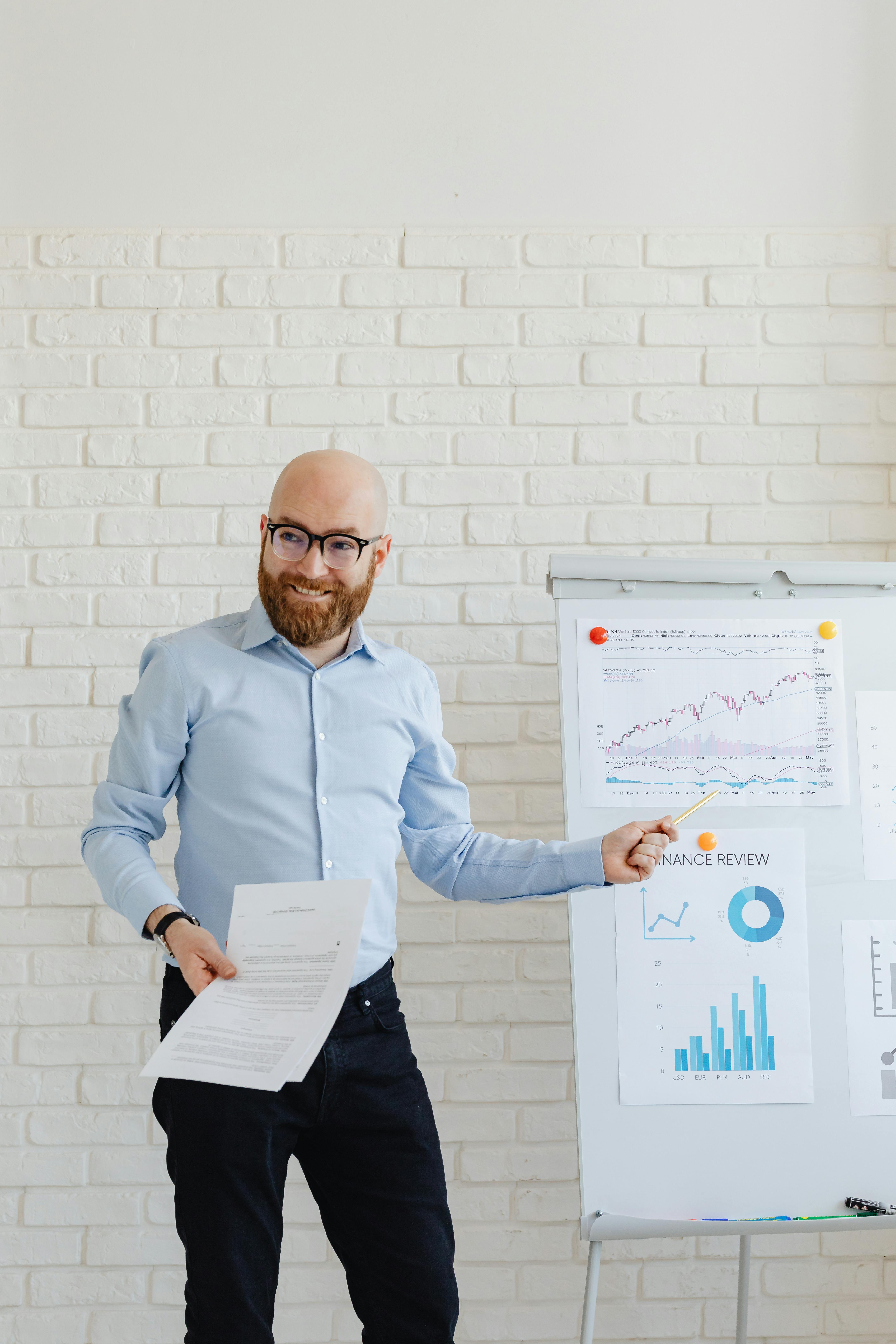 A Man in Corporate Attire Pointing at Charts on a Whiteboard