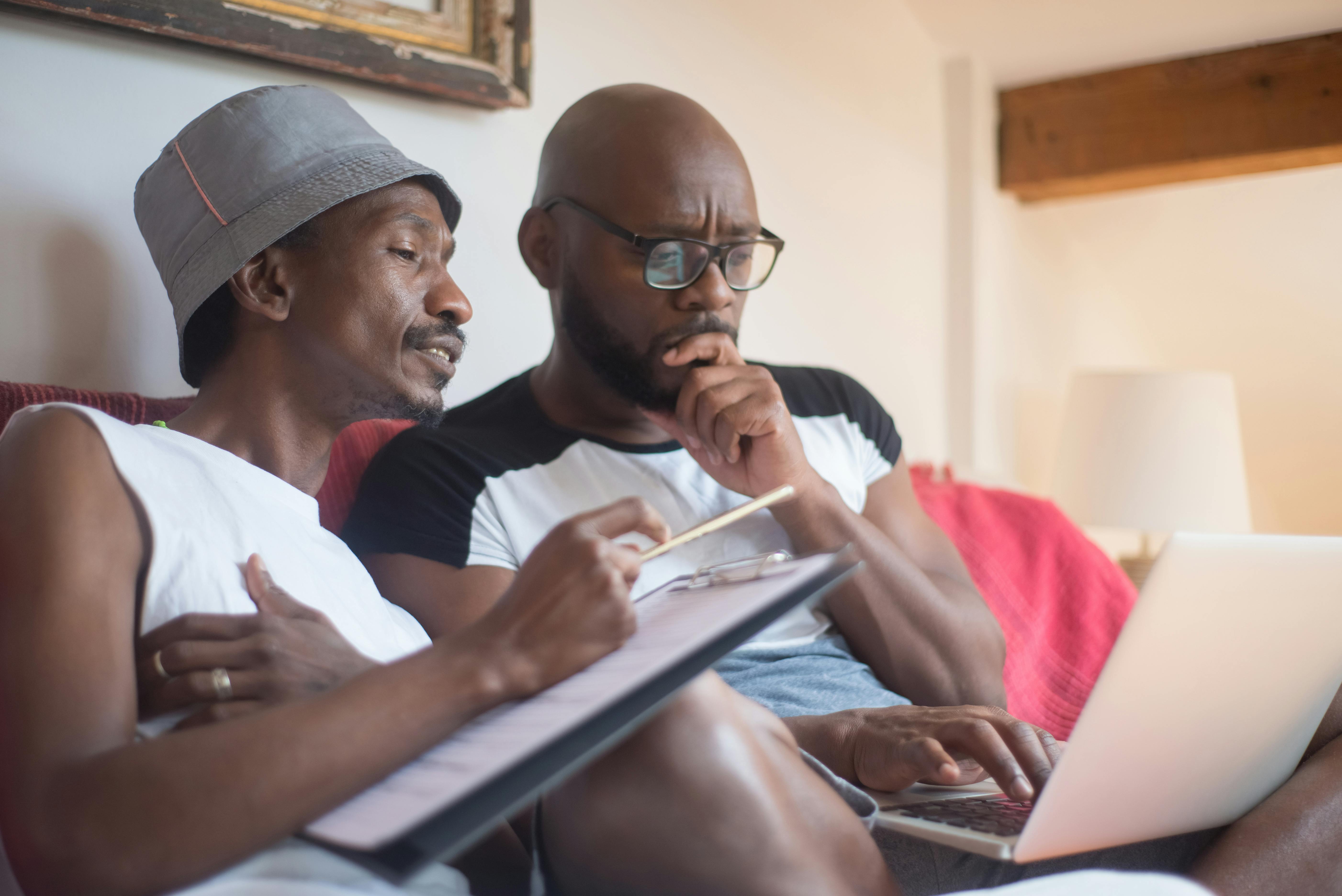 Two Men Sitting on a Sofa Using a Laptop