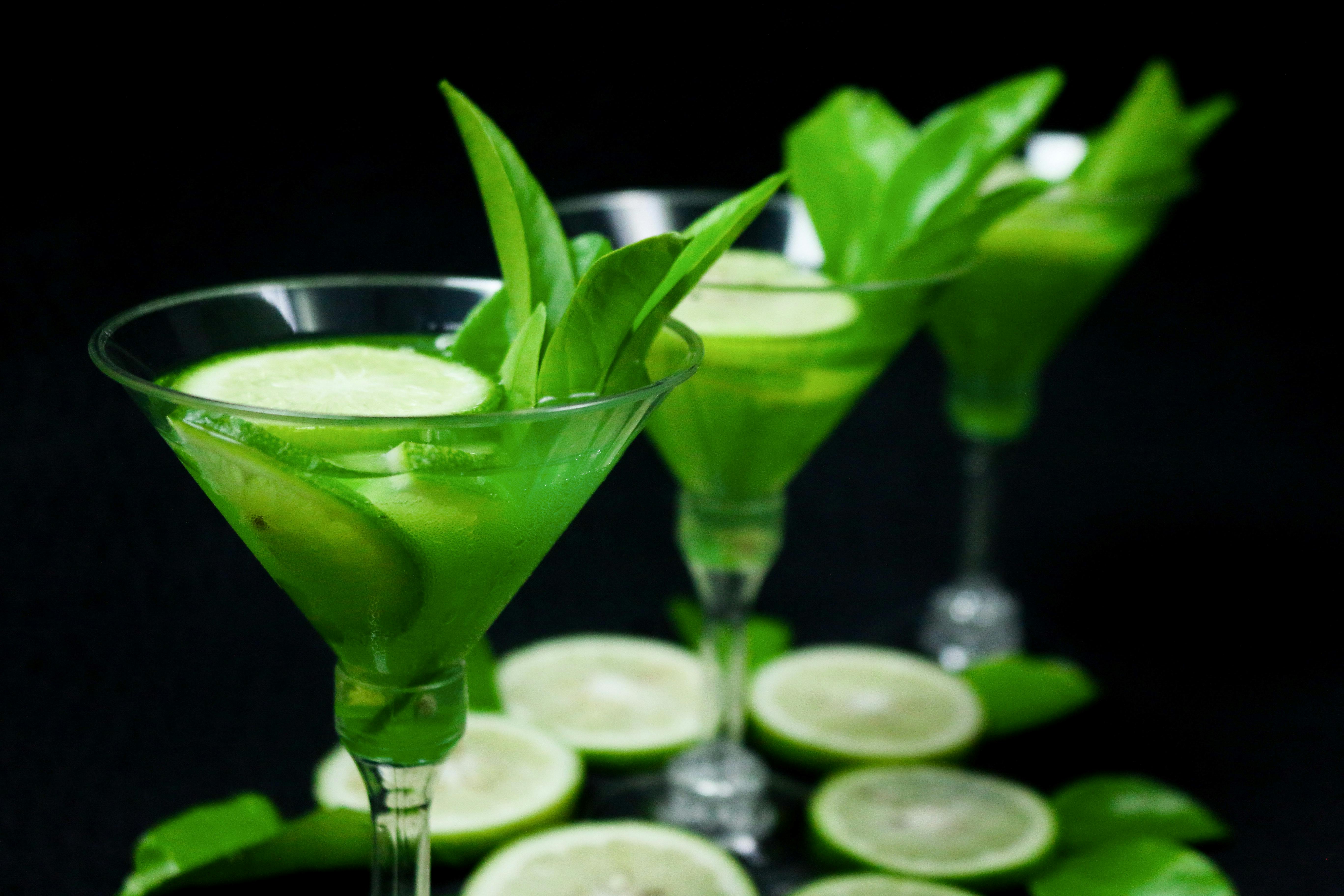 Green Liquid in Clear Cocktail Glass with Lime Slices